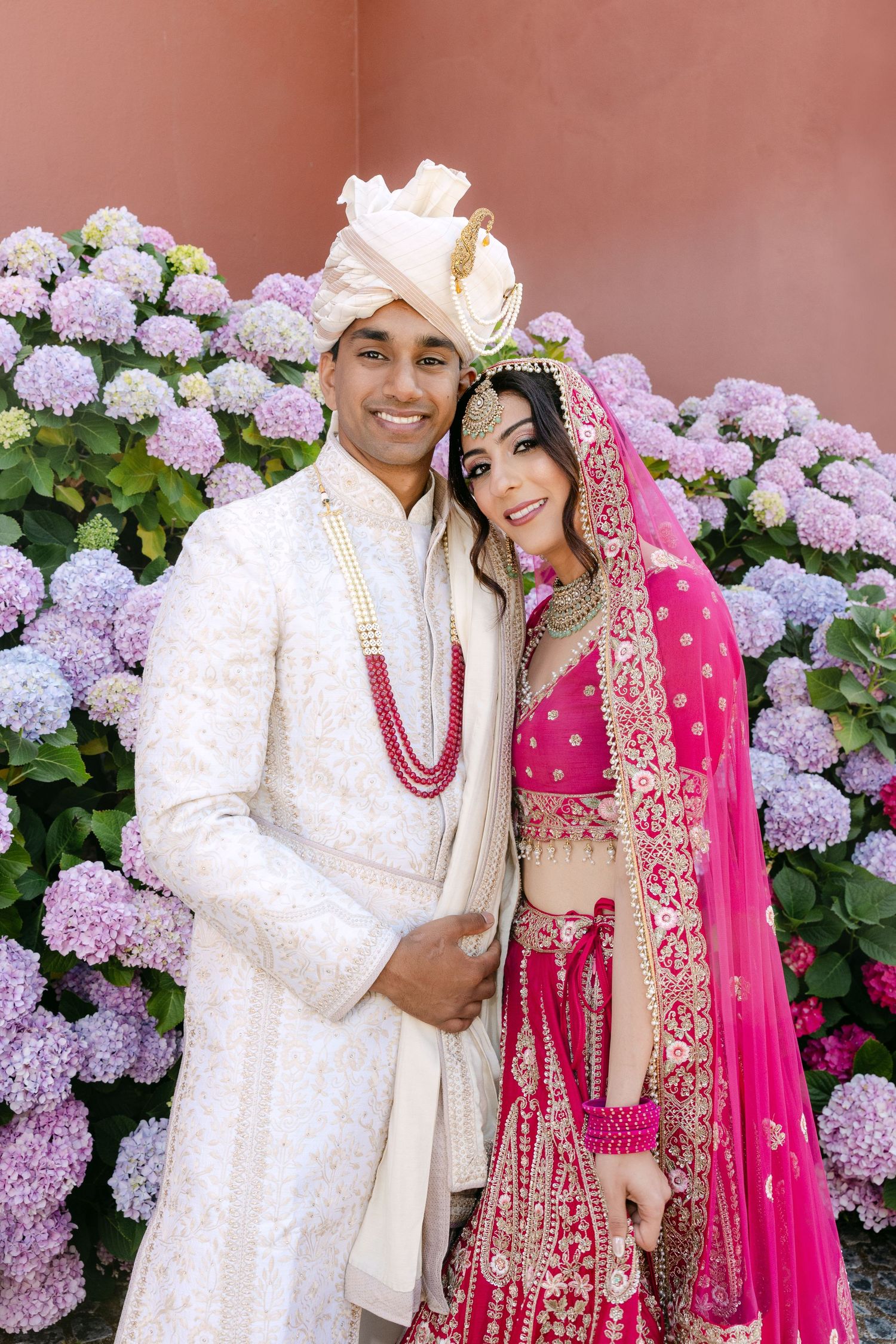 Traditional Indian wedding attire against backdrop of purple hydrangeas.