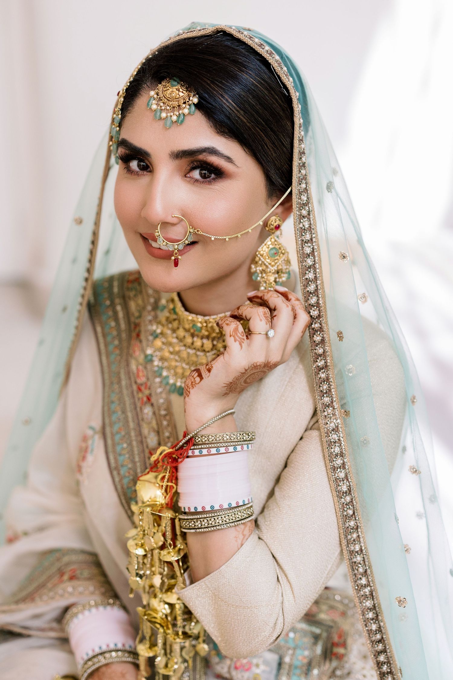 Traditional South Asian bridal attire featuring intricate jewelry and mint green dupatta.
