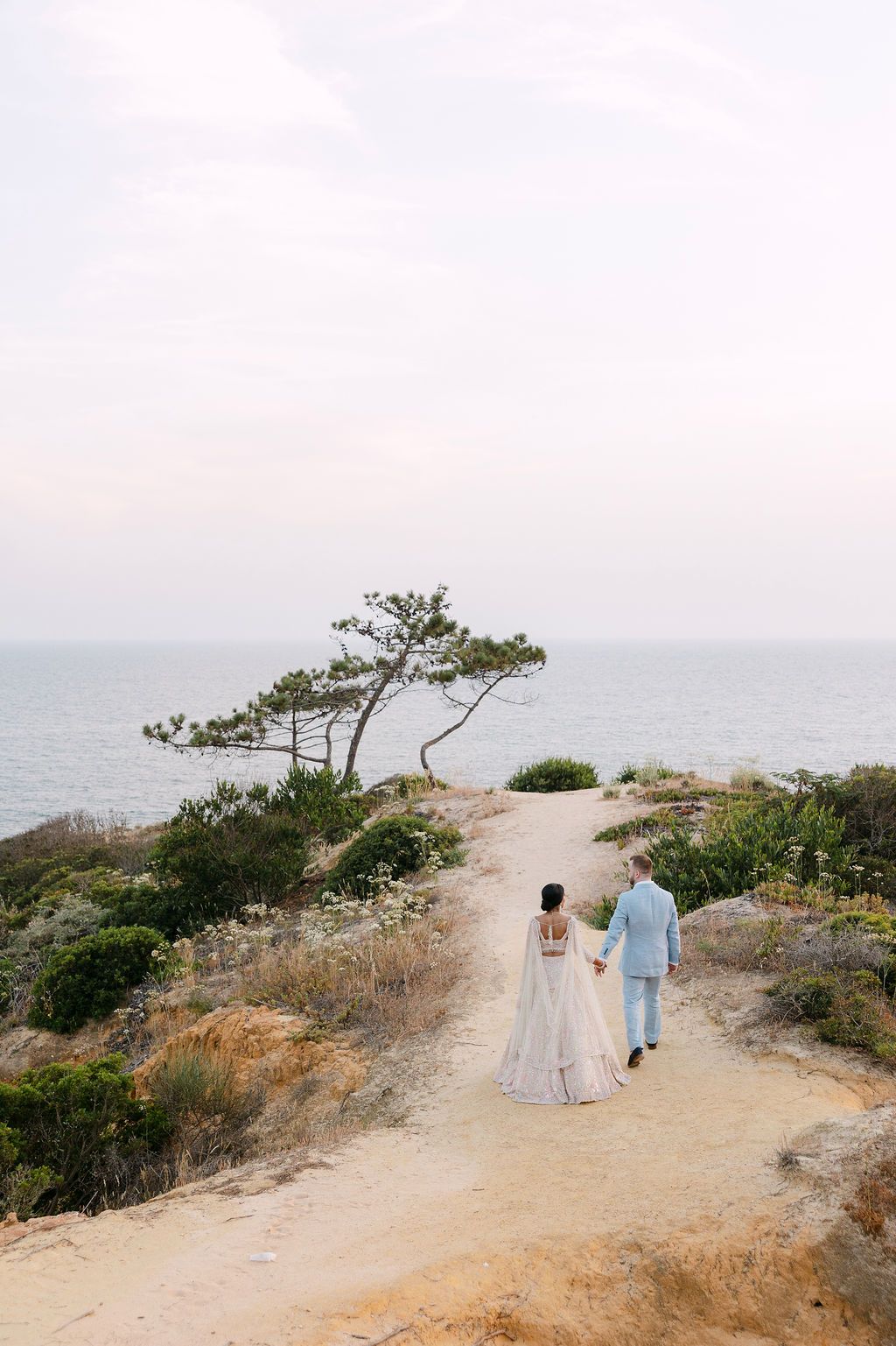 Couple walking along a scenic coastal path with ocean views in the background.