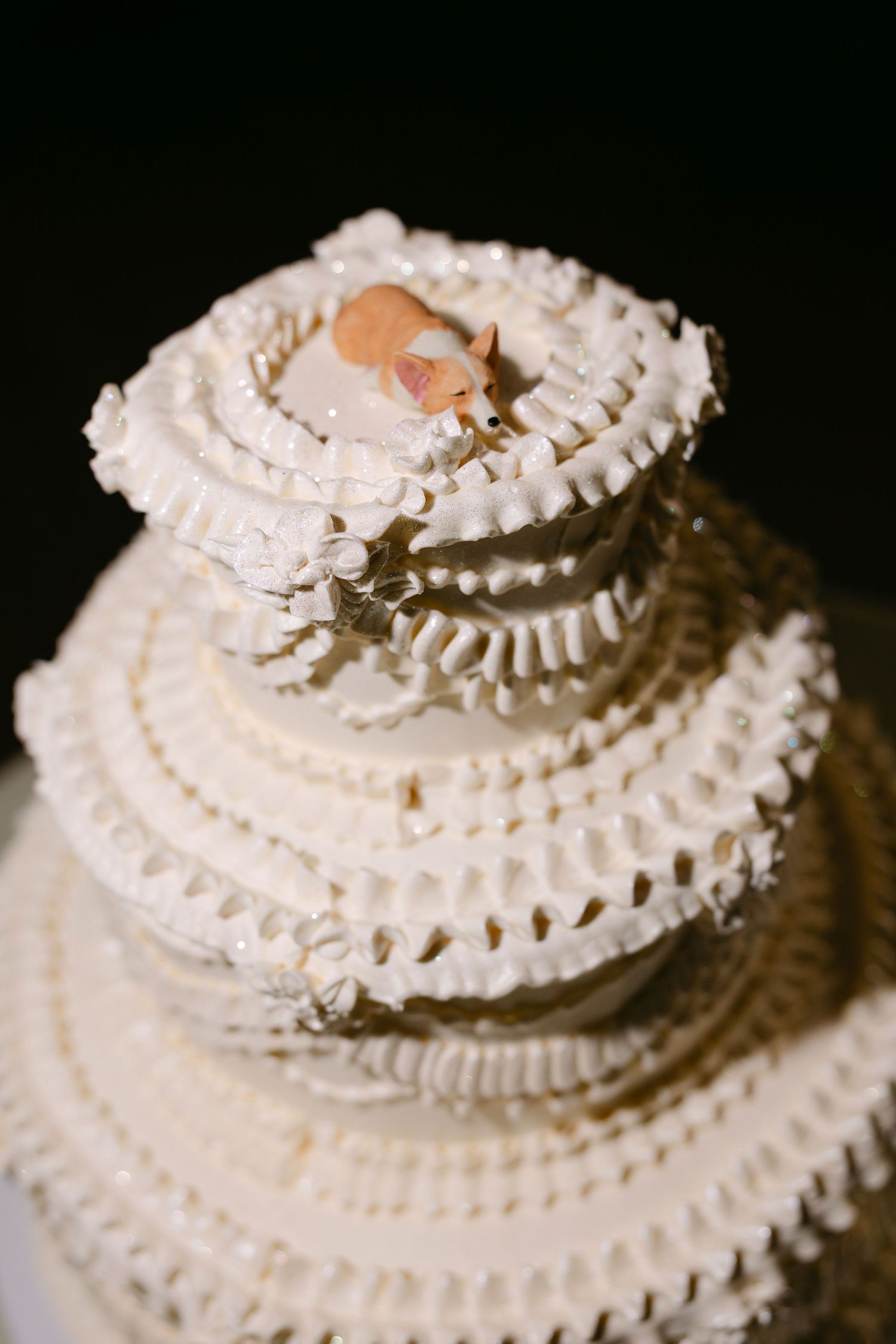 Elegant white wedding cake with intricate piped details and delicate ruffled tiers.