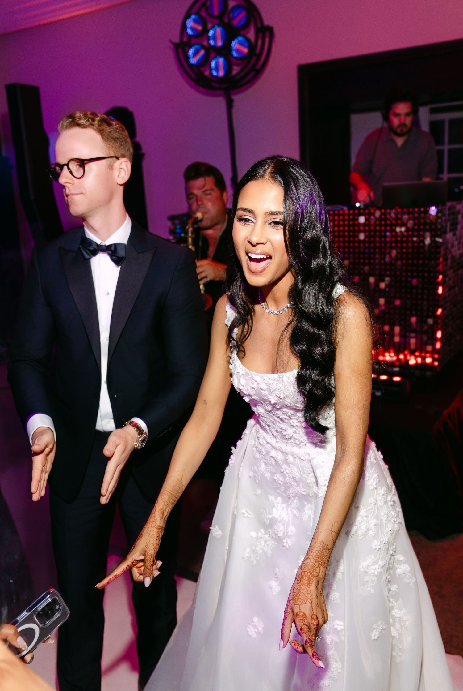 Wedding celebration on dance floor with purple ambient lighting and festive atmosphere.