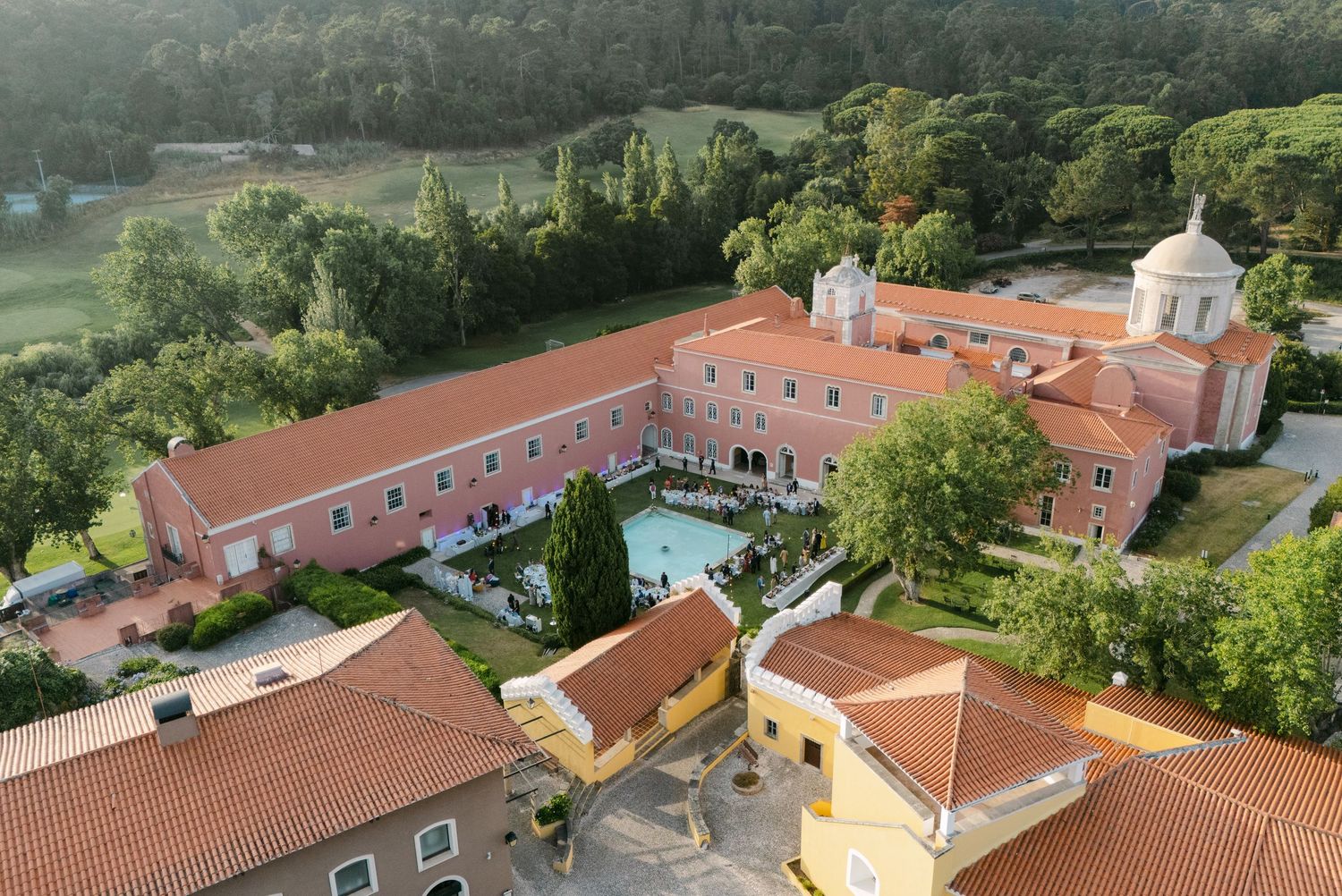 Aerial view of pink Mediterranean-style resort complex with red tile roofs and white domes.