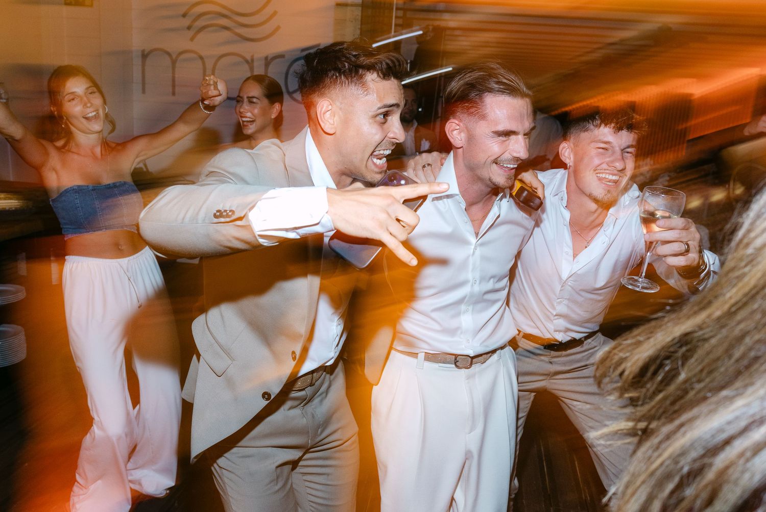Lively dance floor celebration with motion blur in warm orange lighting.