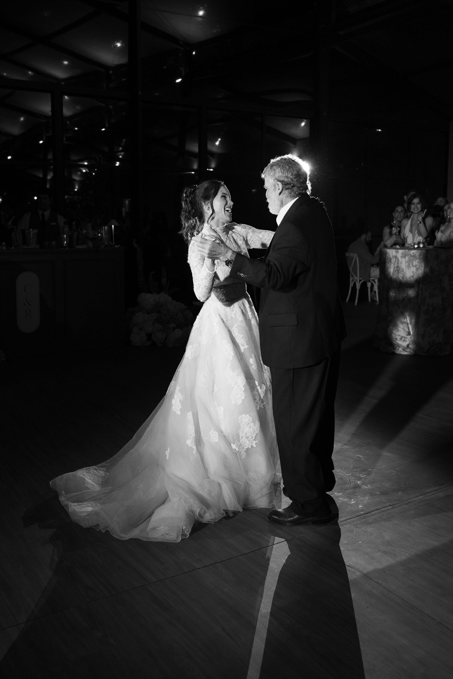 A couple shares their first dance at their wedding reception in a darkened ballroom.