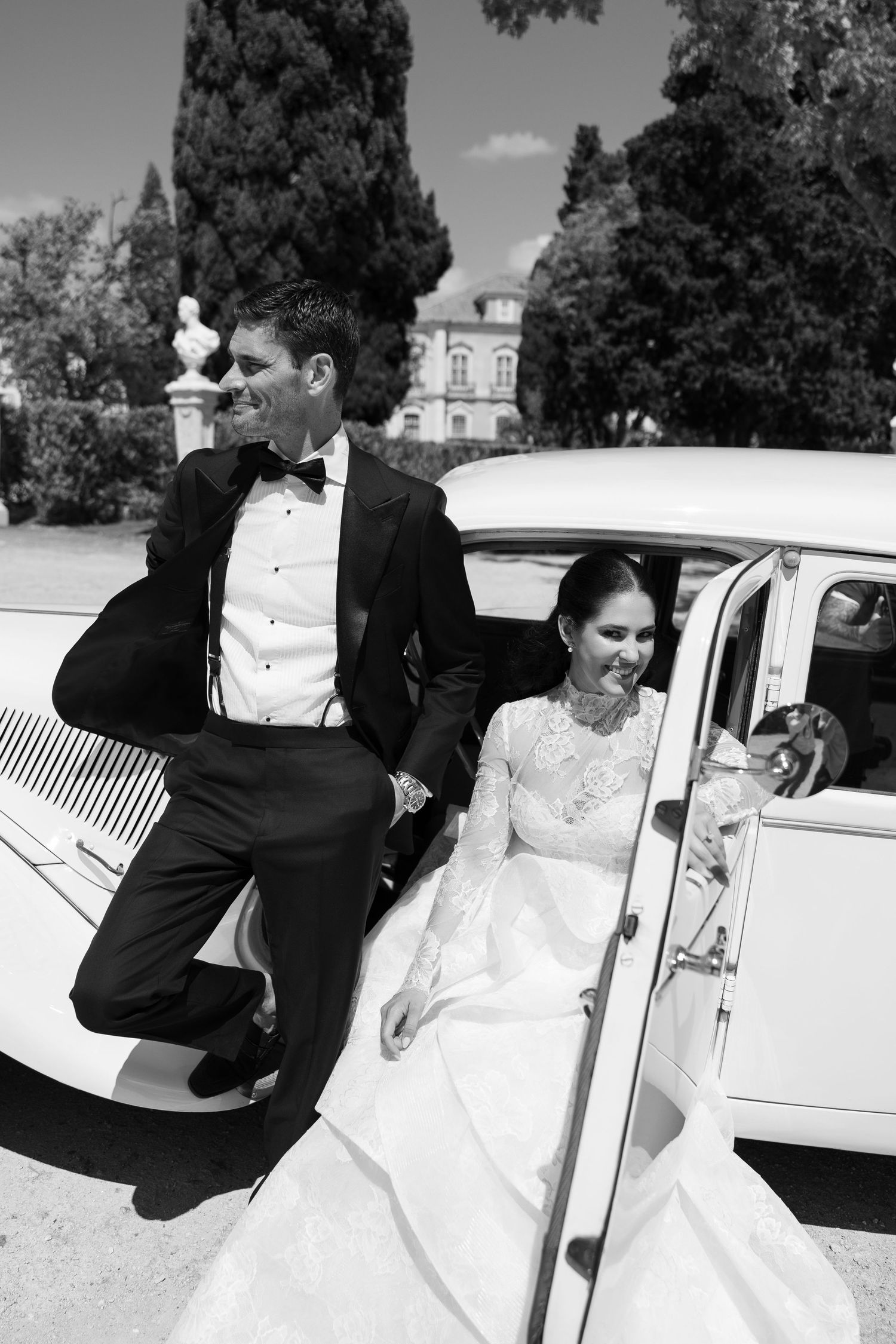 Classic white vintage car parked outdoors with wedding attire visible through the windows.