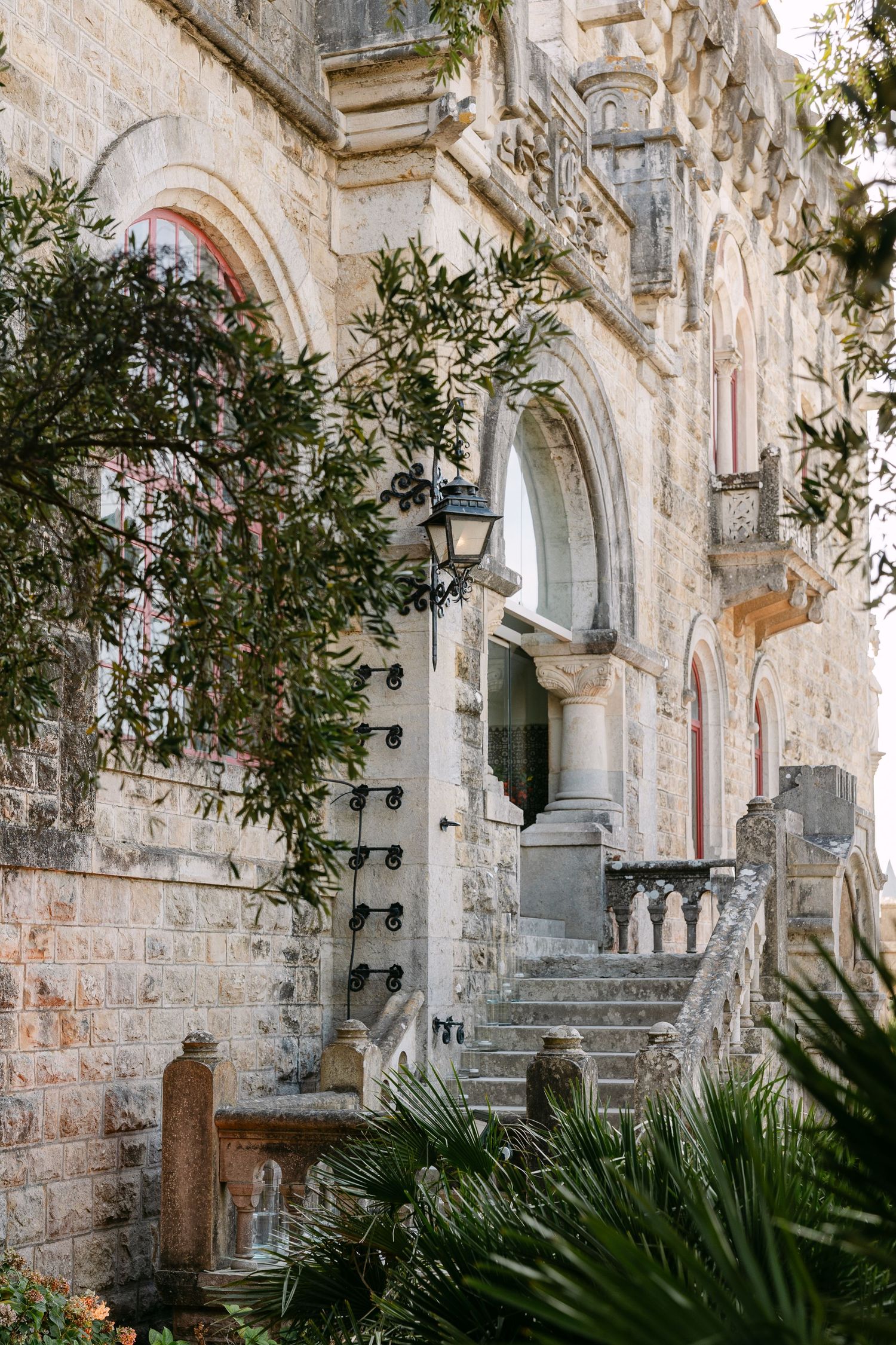 Stone church exterior with arched windows and Mediterranean foliage.