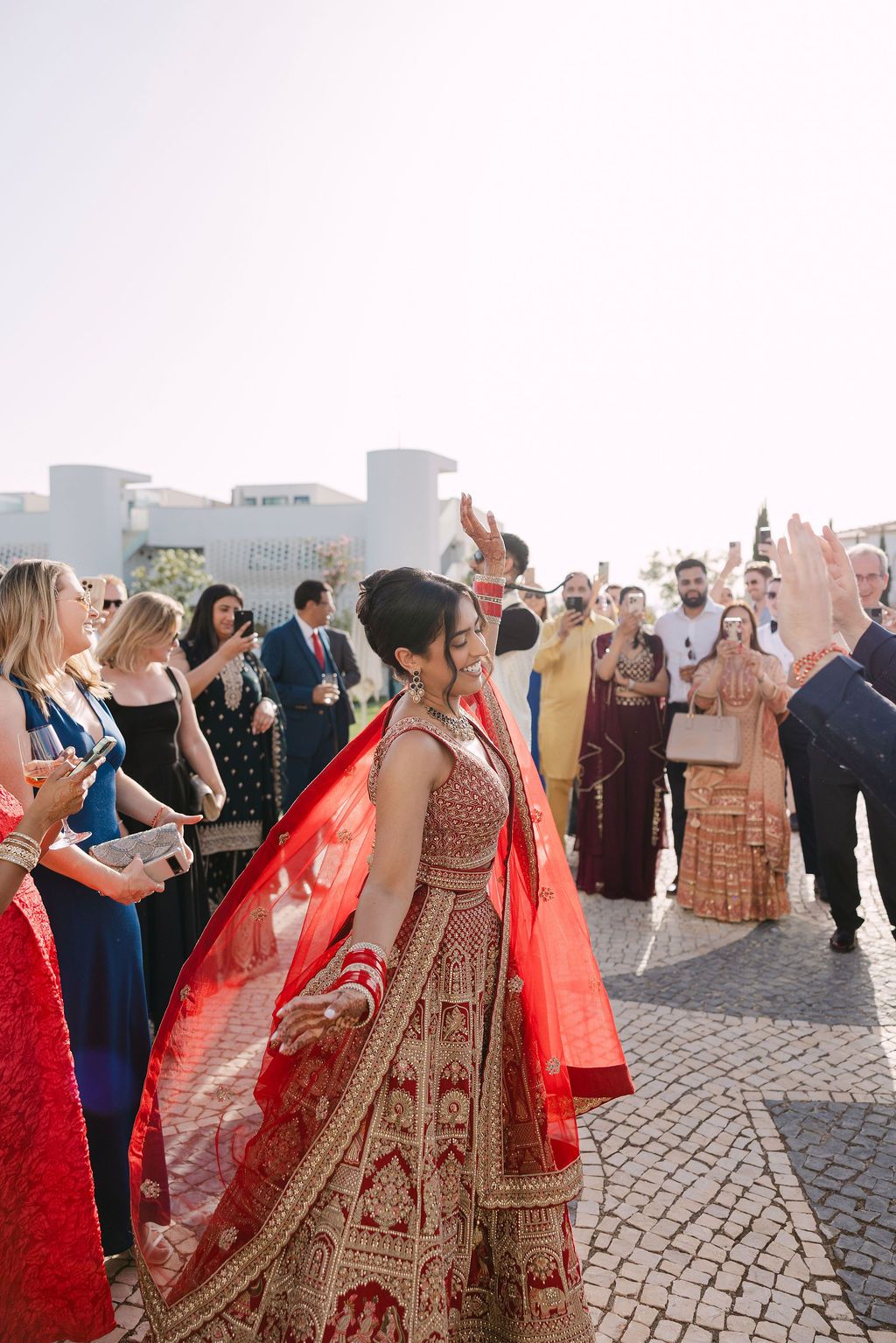 Guests dancing and celebrating at an outdoor rooftop wedding reception with traditional Indian attire and decor.
