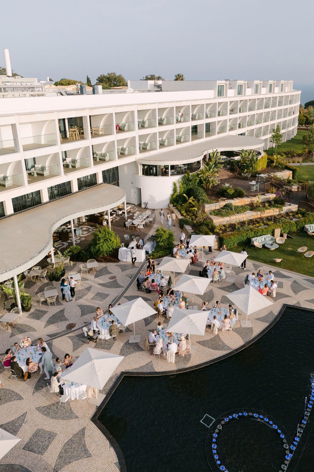Aerial view of a modern white coastal wedding venue with geometric patio design.
