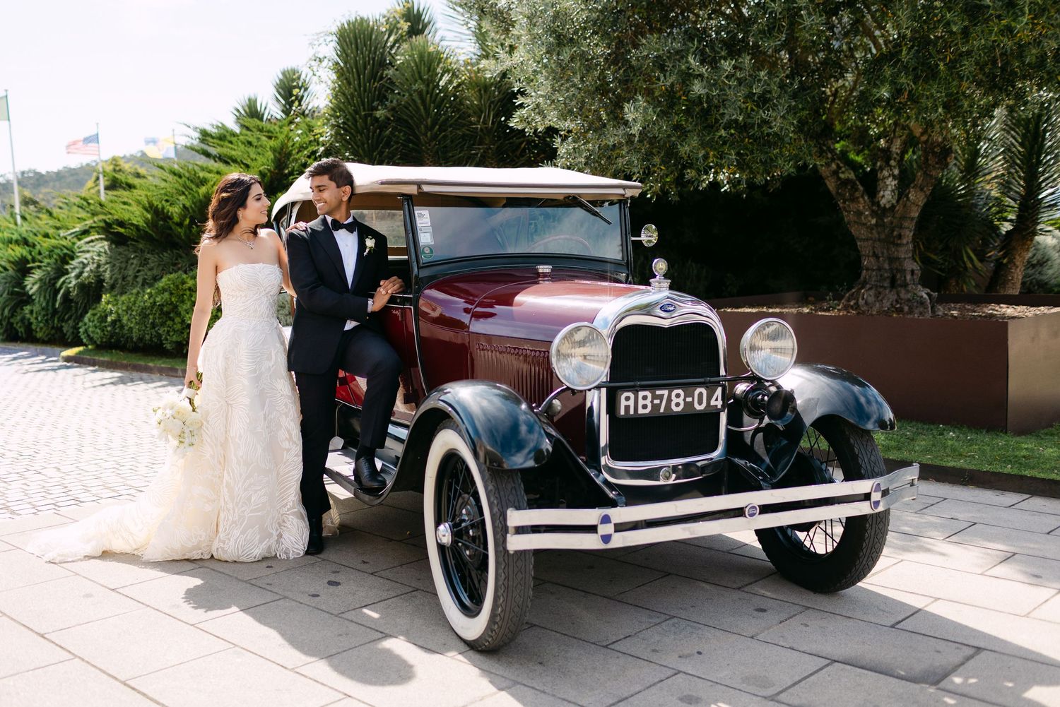 Classic vintage cars parked outside with palm trees and wedding decorations.