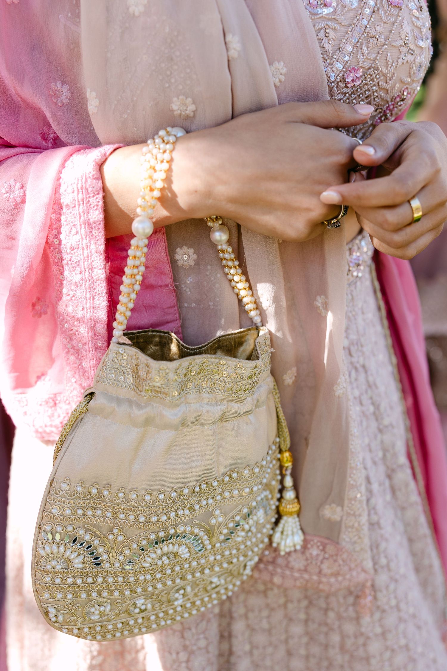 Close-up of ornate beaded purse and pearl bracelet with pink and gold formal attire.