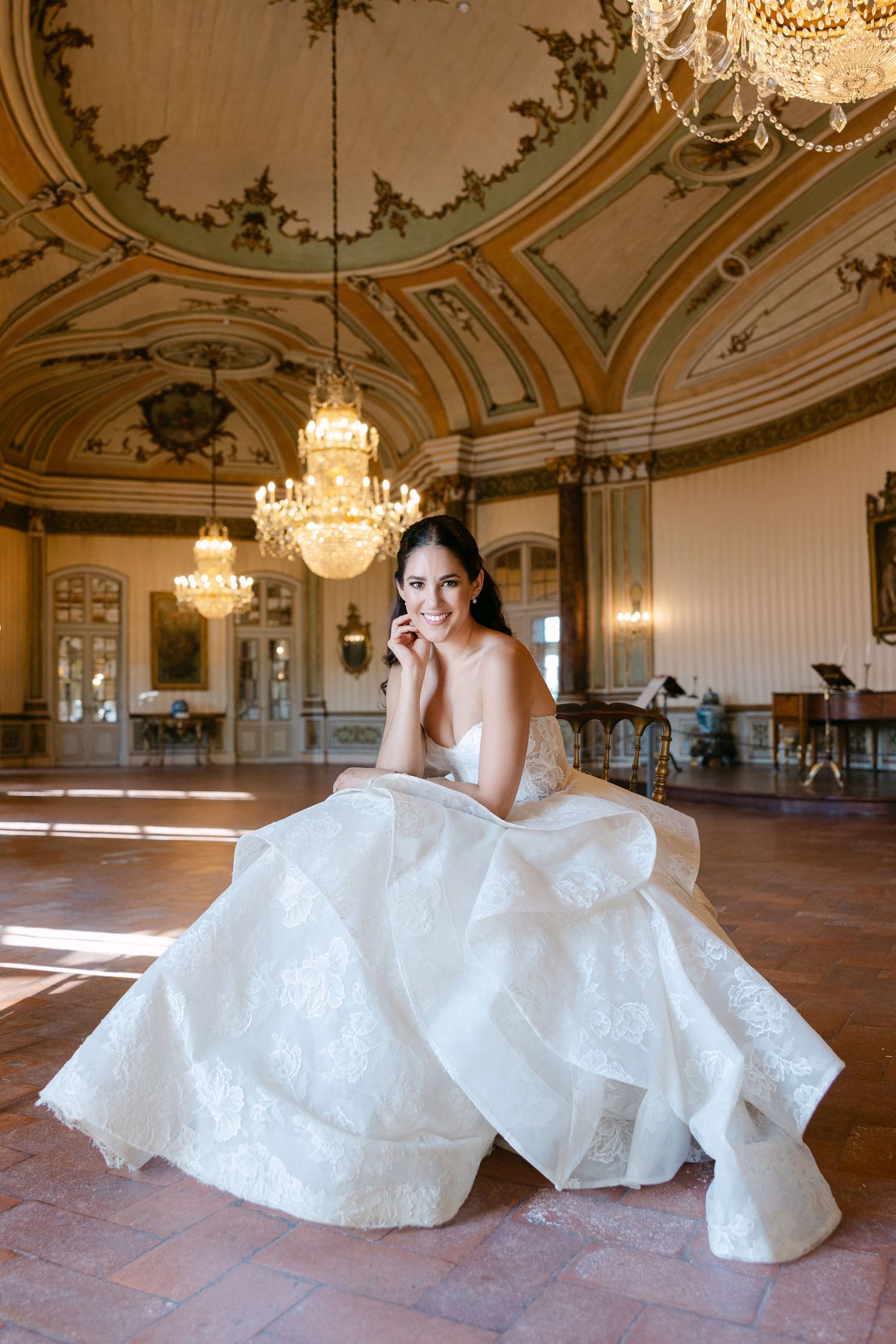 Elegant ballroom with ornate ceiling, crystal chandeliers and sunlit wooden floors.