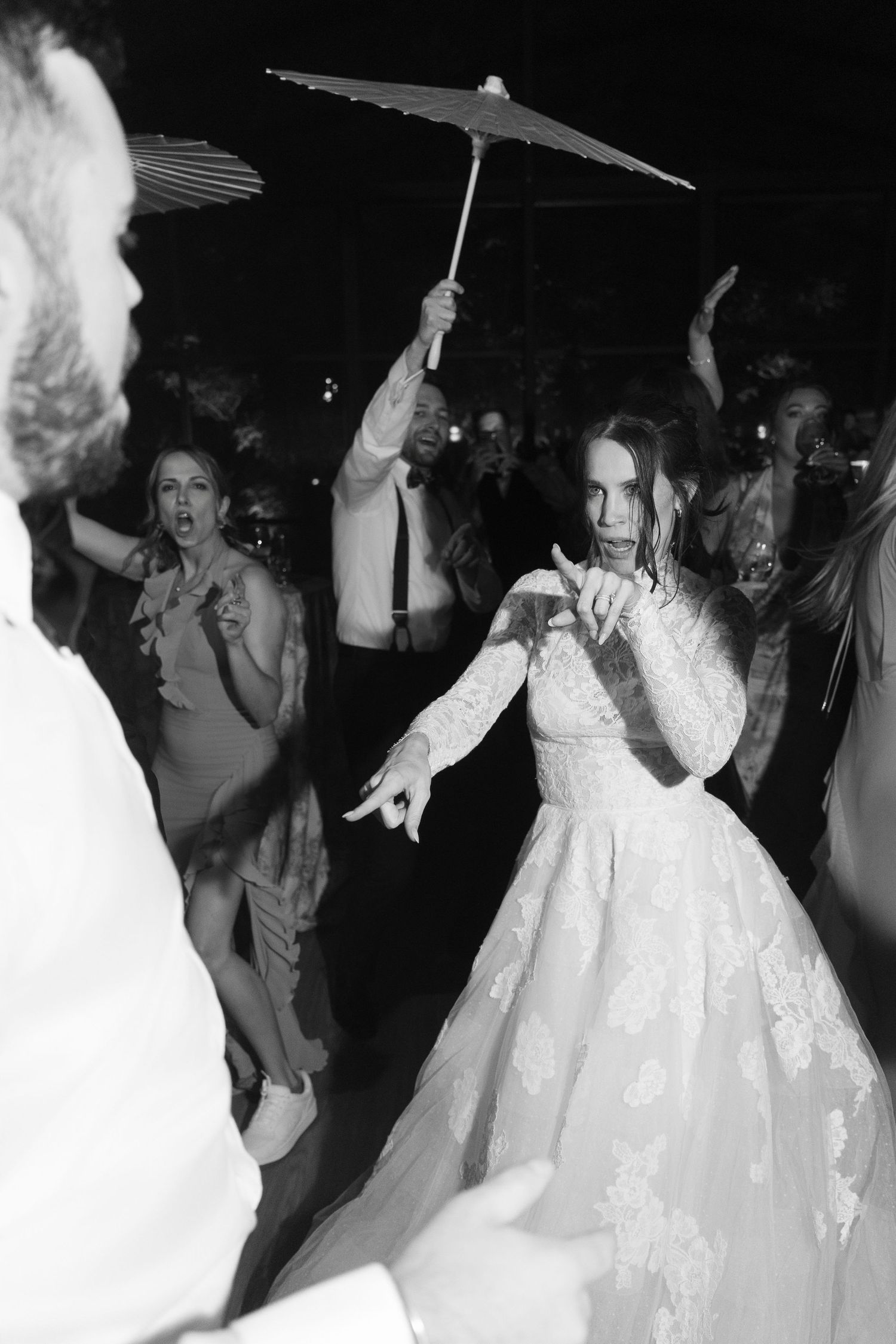 Wedding guests dance joyfully in formal attire under evening lighting.