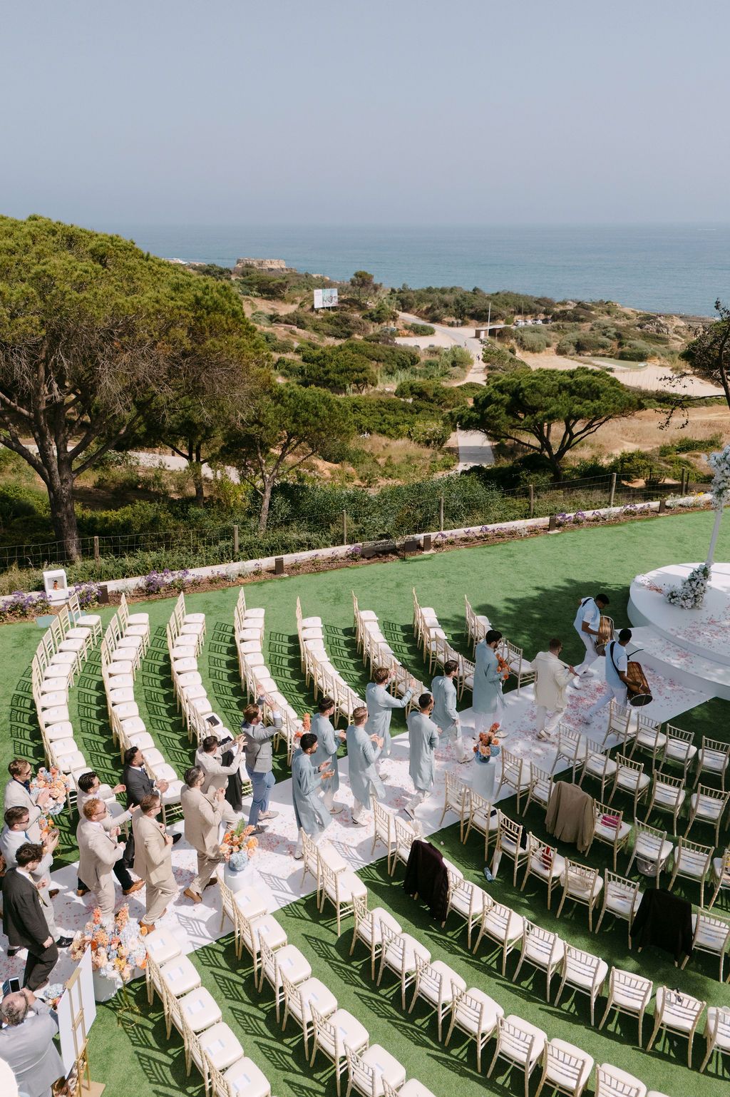 Outdoor wedding ceremony setup with white chairs arranged in rows overlooking an ocean view.
