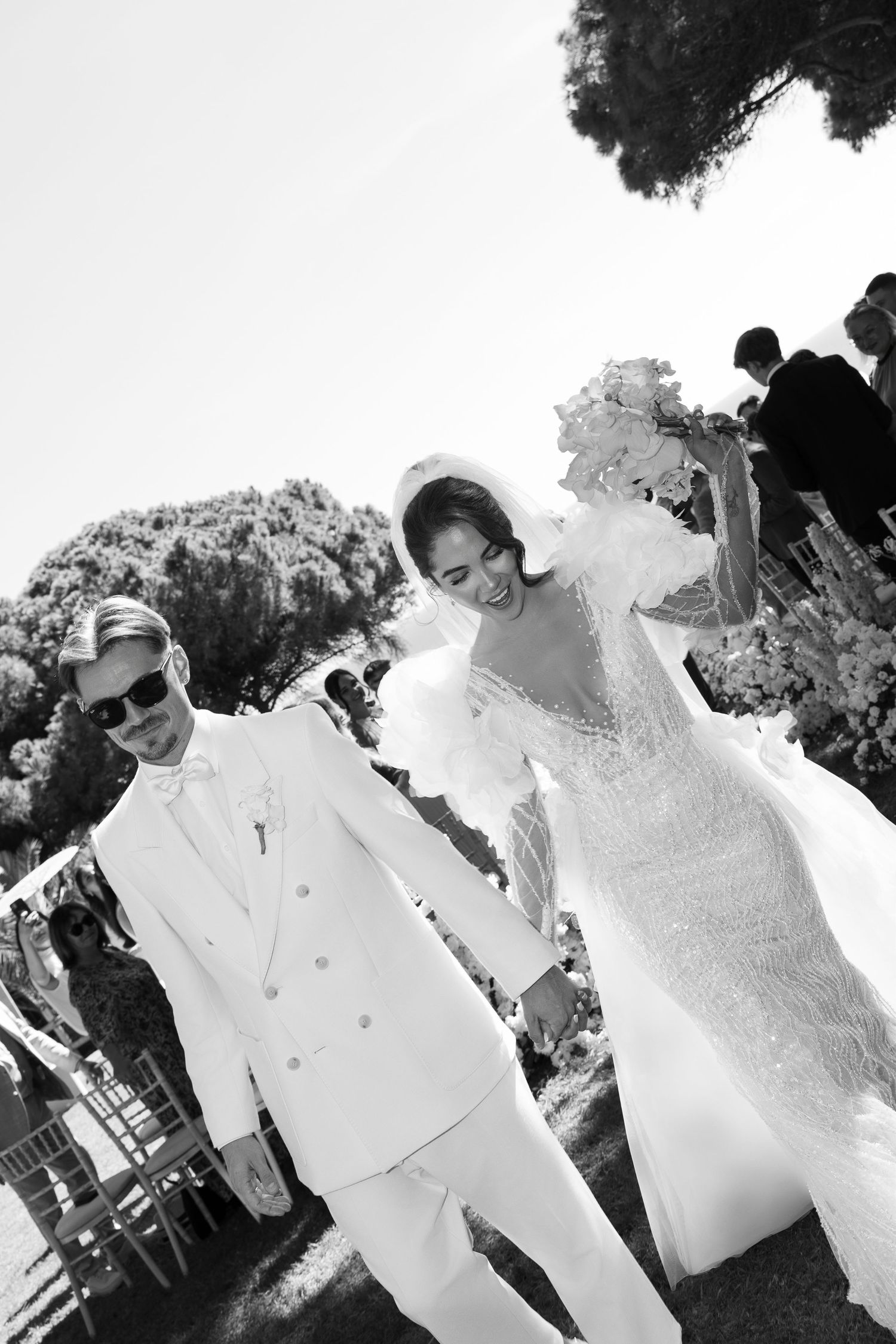 Wedding guests in white attire gathered for an outdoor celebration.