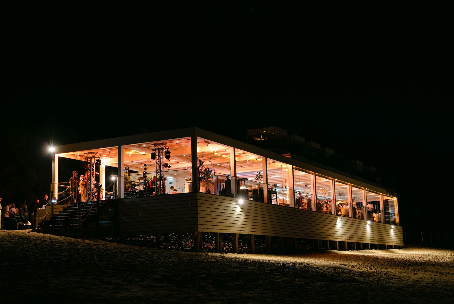Illuminated outdoor wedding reception venue at night with string lights.