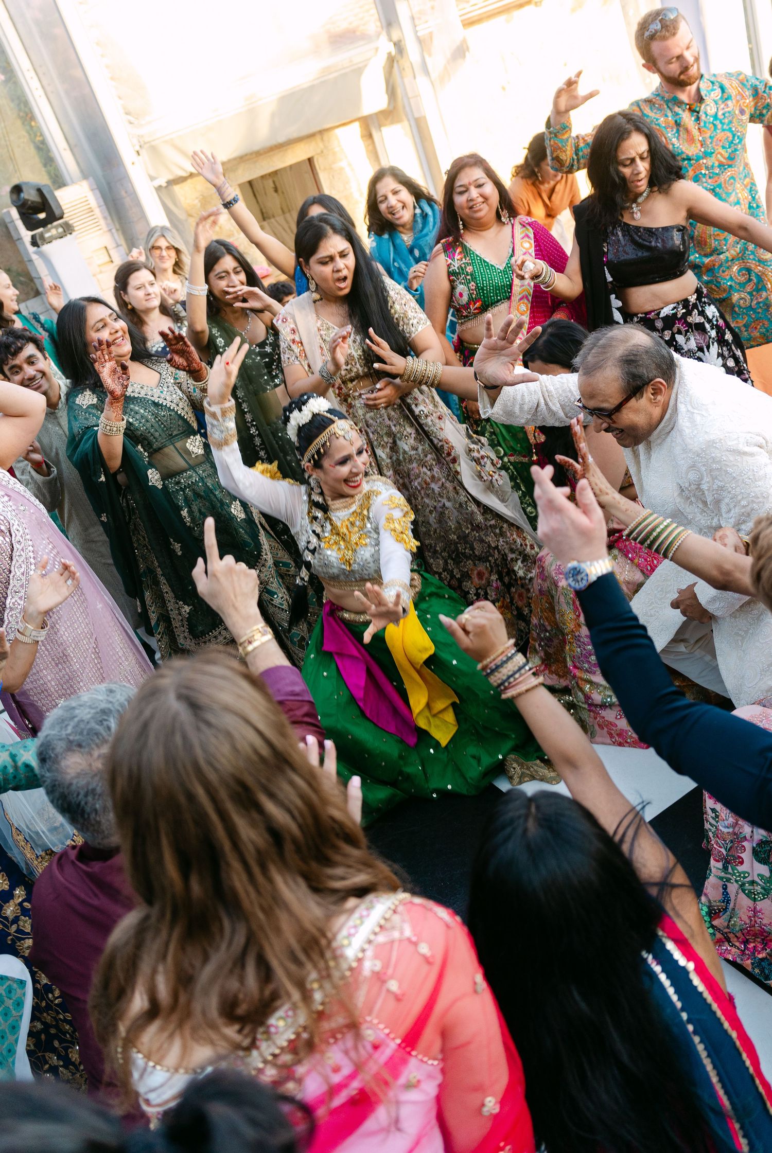 Large group of wedding guests dancing and celebrating together at a lively reception.