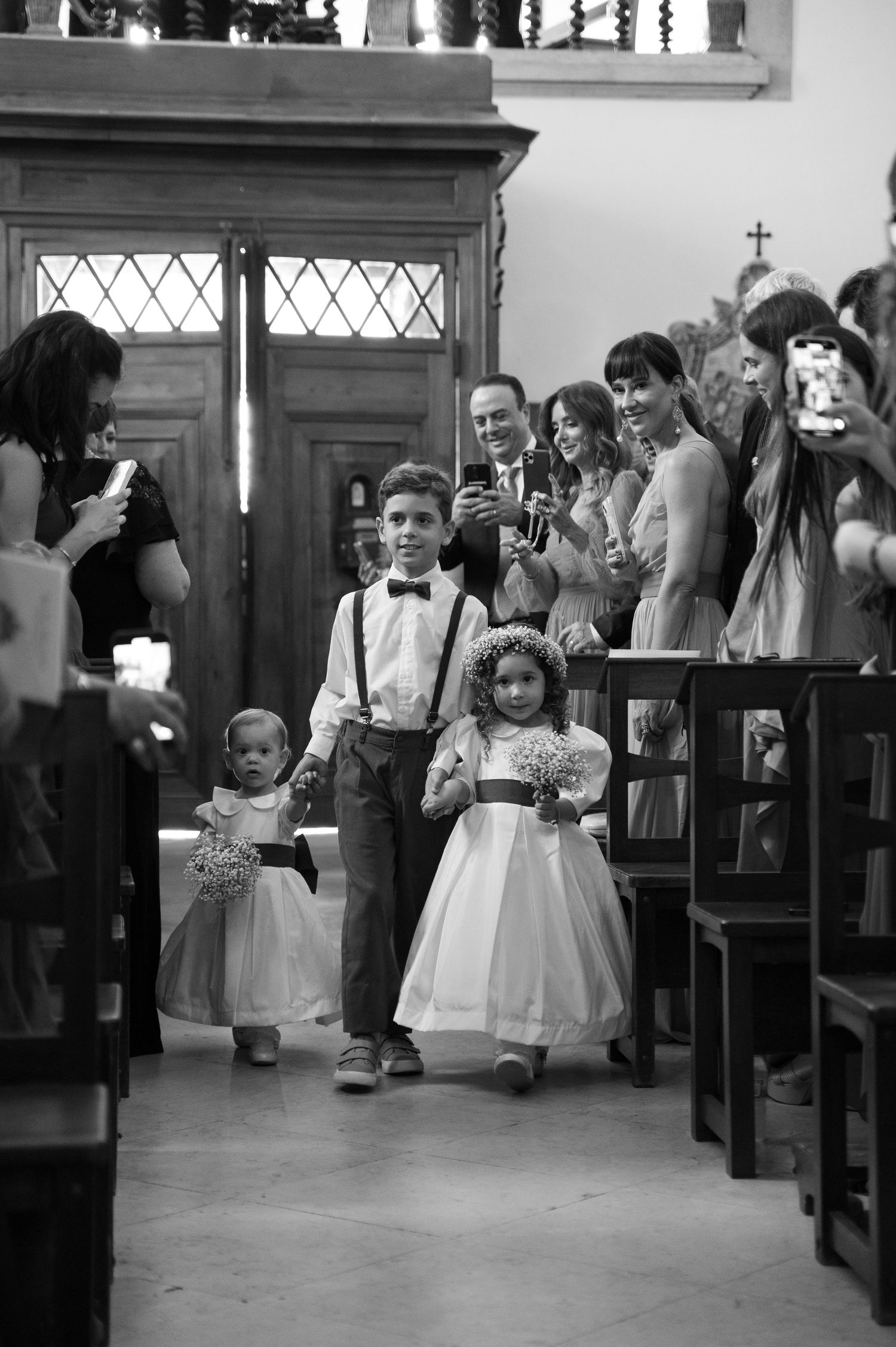 Black and white photograph of young attendants walking down the church aisle during a ceremony.