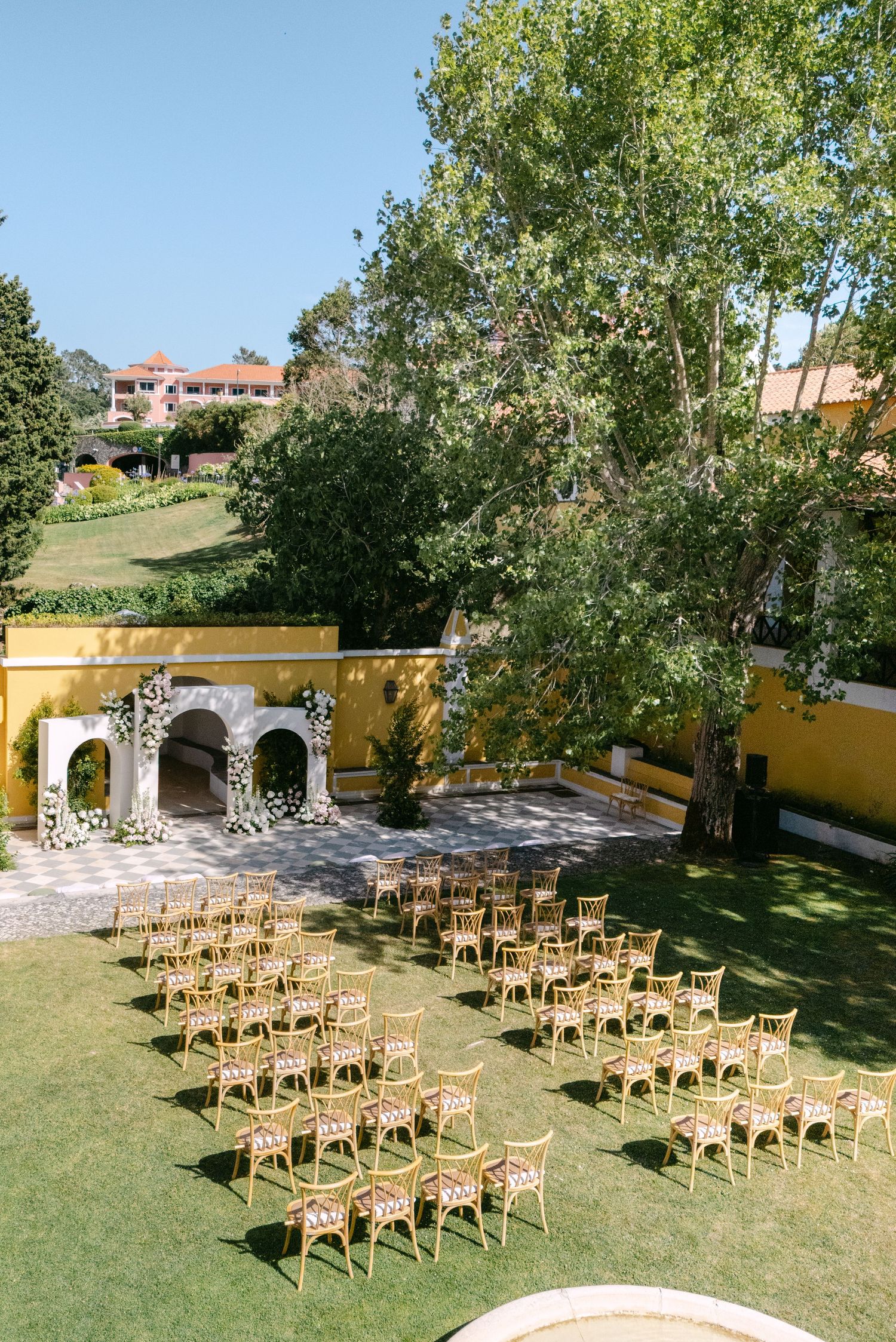Wooden chairs arranged in rows on a green lawn for an outdoor ceremony.