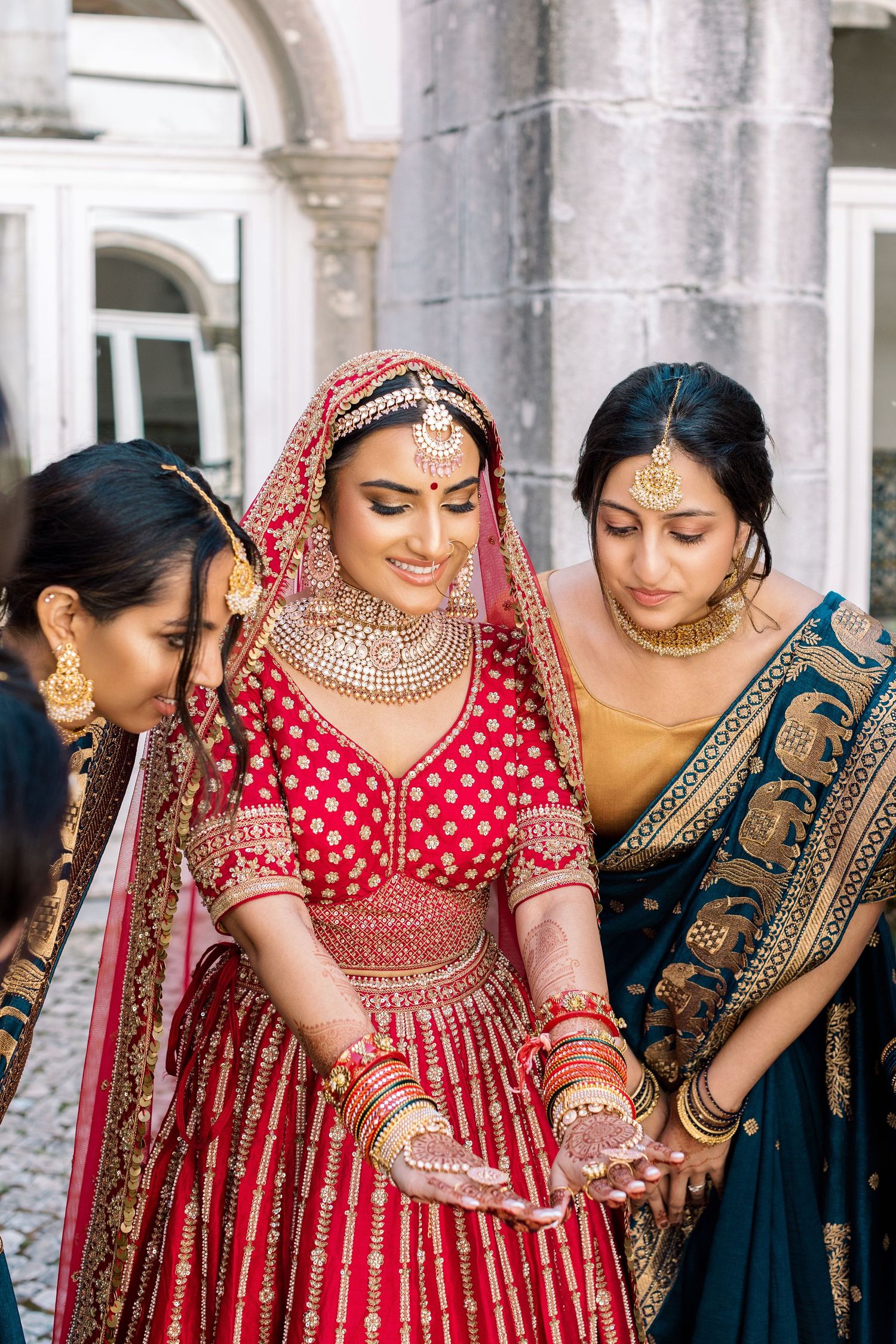 Group of women in traditional Indian wedding attire featuring red and navy blue sarees.