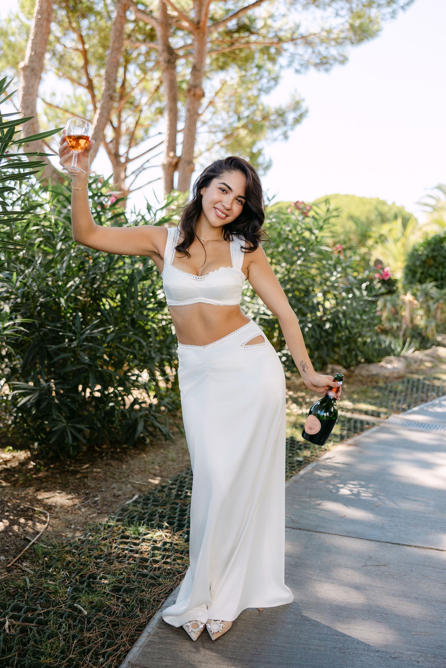 Woman in white dress posing playfully on outdoor pathway.
