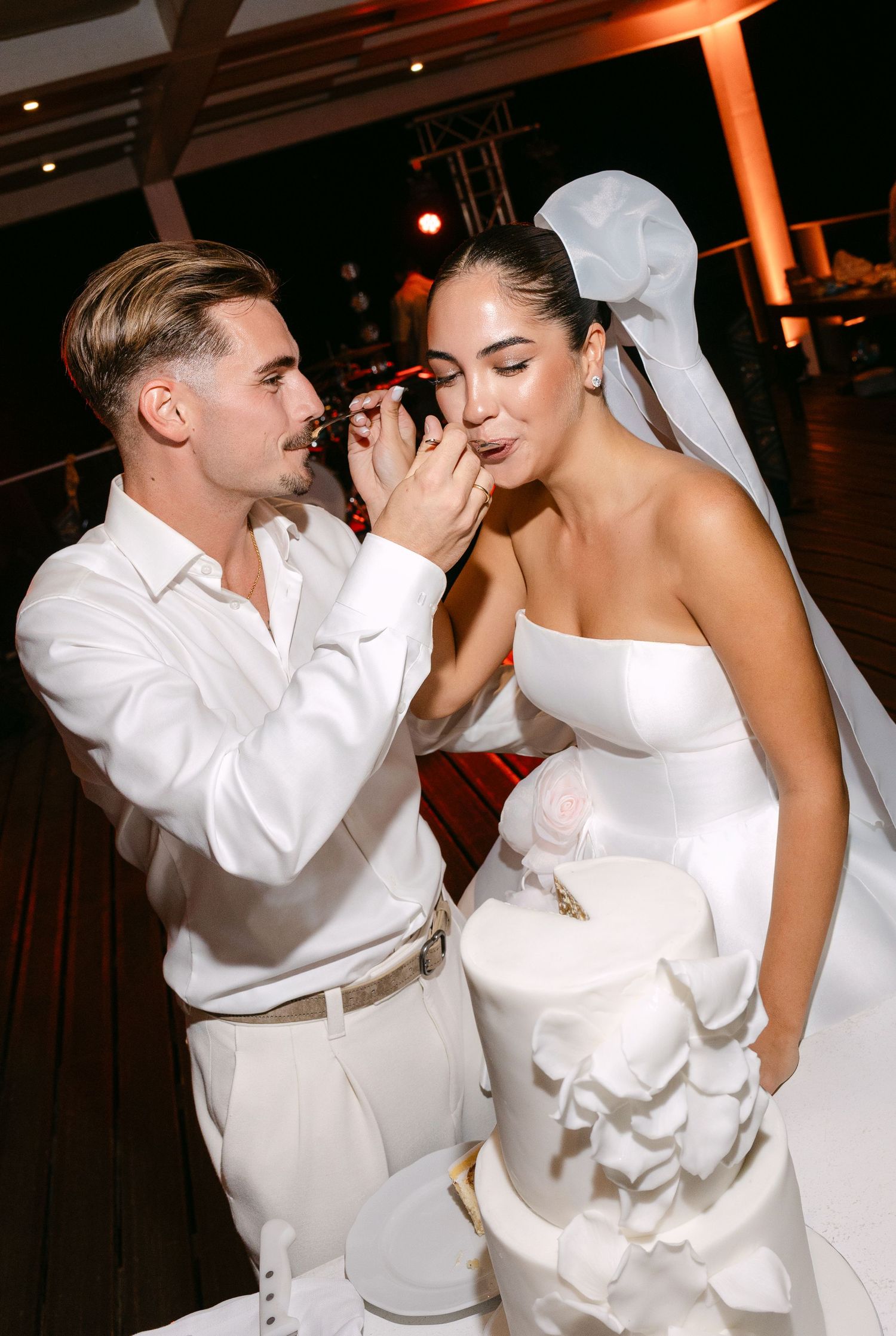 Couple in white attire sharing intimate dance moments at wedding reception.