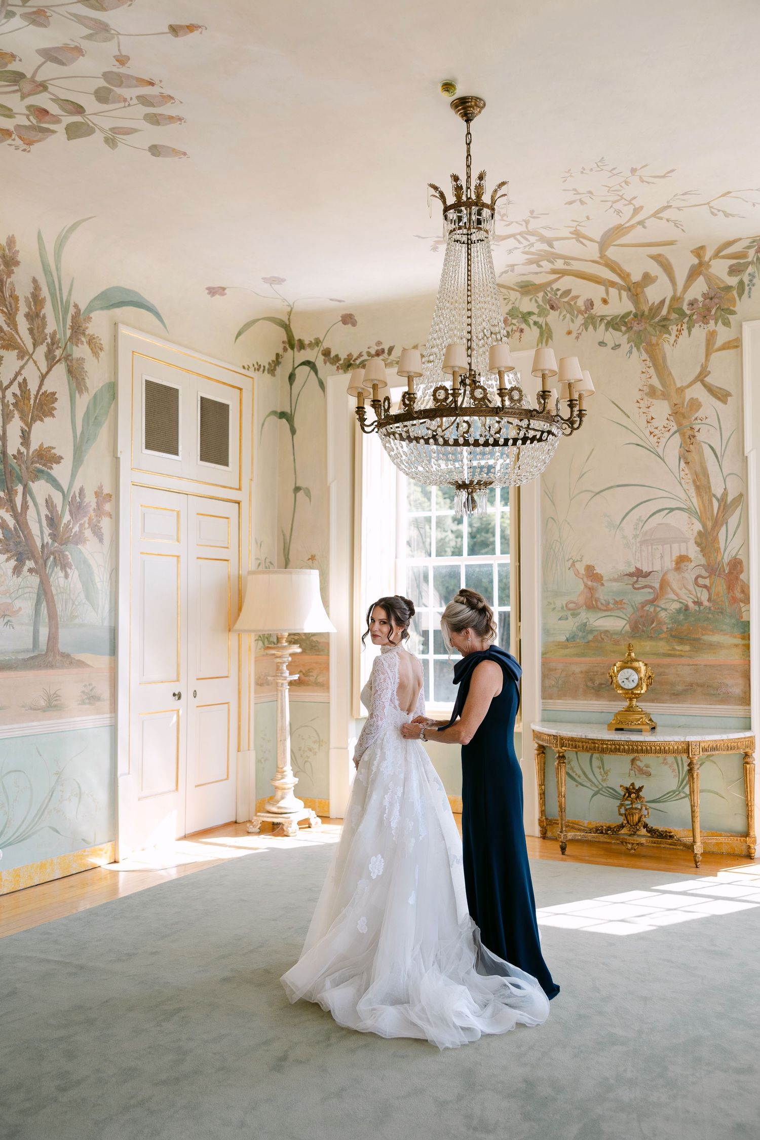 Elegant room with mural walls and chandelier showcasing wedding preparations.