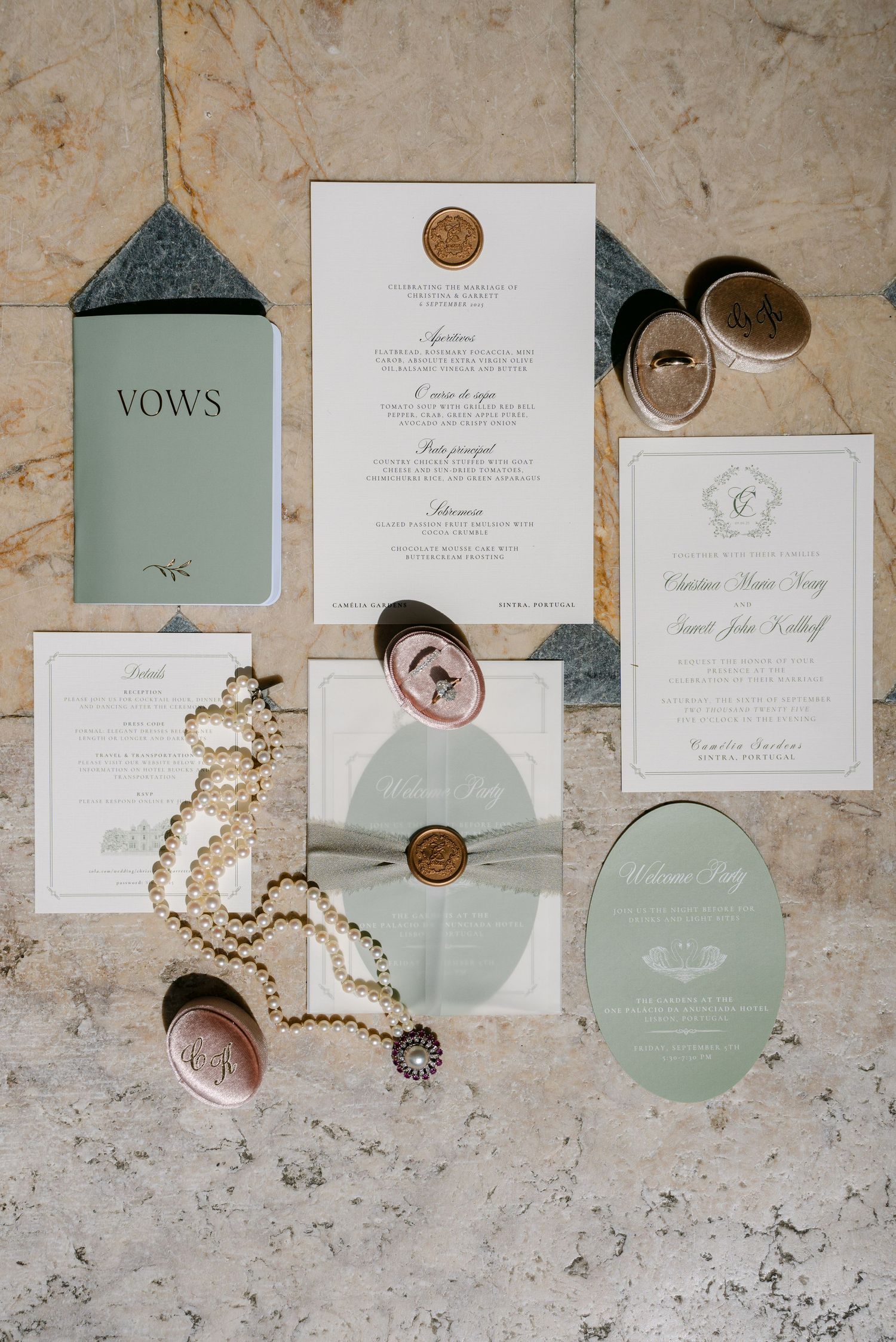 Wedding stationery flat lay featuring vow books, invitations, and pearl accessories in sage green and white.