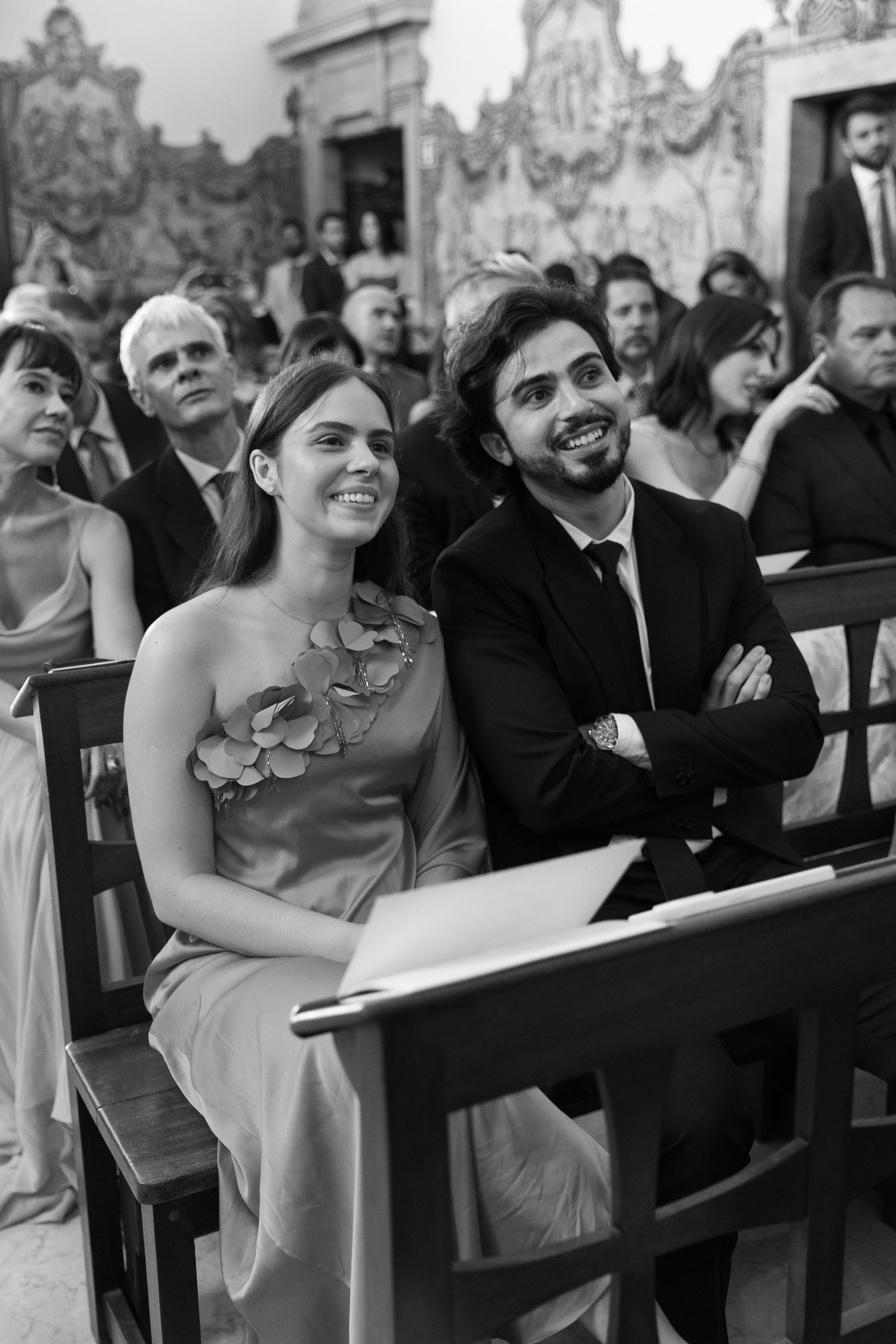 Wedding guests watching the ceremony from wooden church pews.
