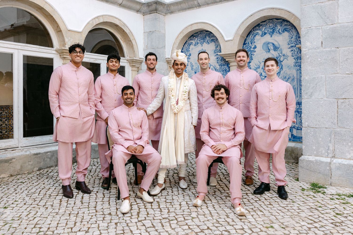 Wedding party poses for a group photo wearing coordinated pink suits.