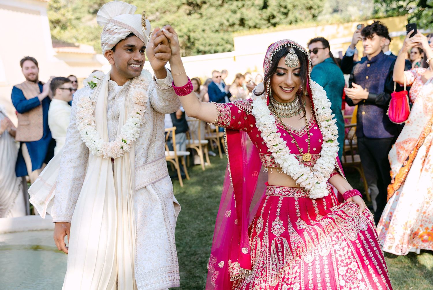 Festive wedding celebration with guests in traditional Indian attire dancing outdoors.
