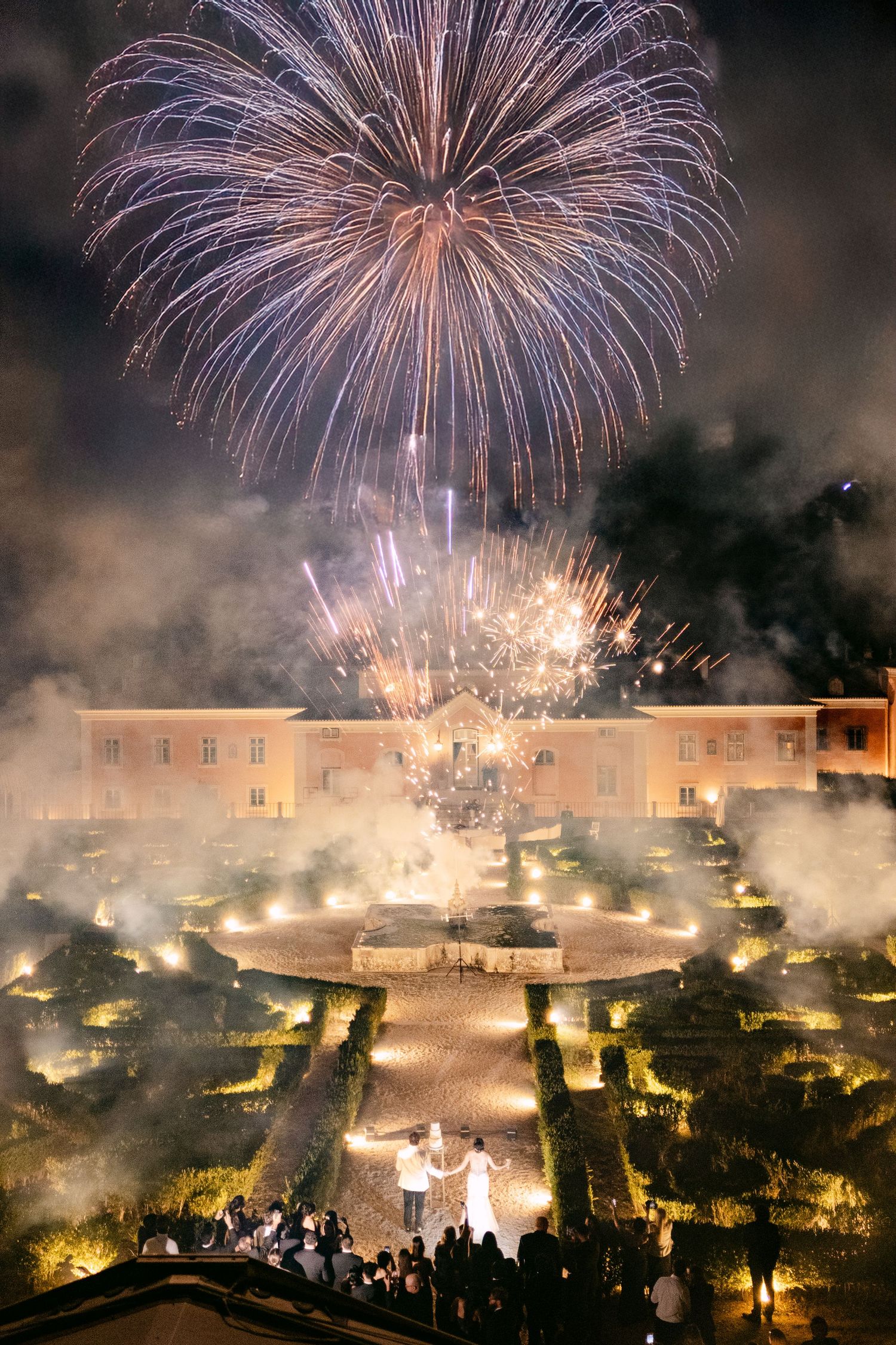 Spectacular fireworks display illuminates a cityscape with bright bursts of light against the night sky.