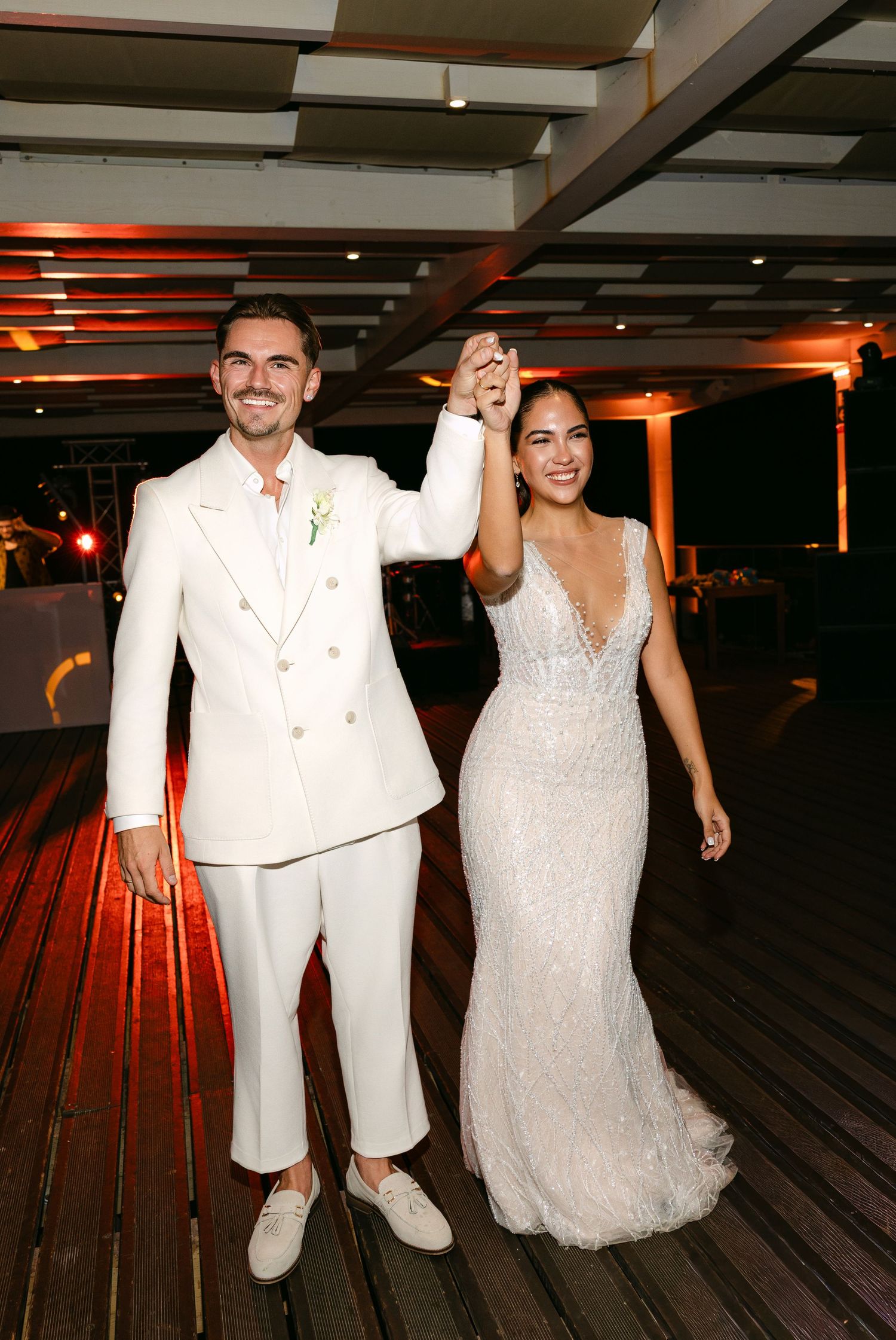 Wedding couple dancing and celebrating on a wooden deck with warm lighting.