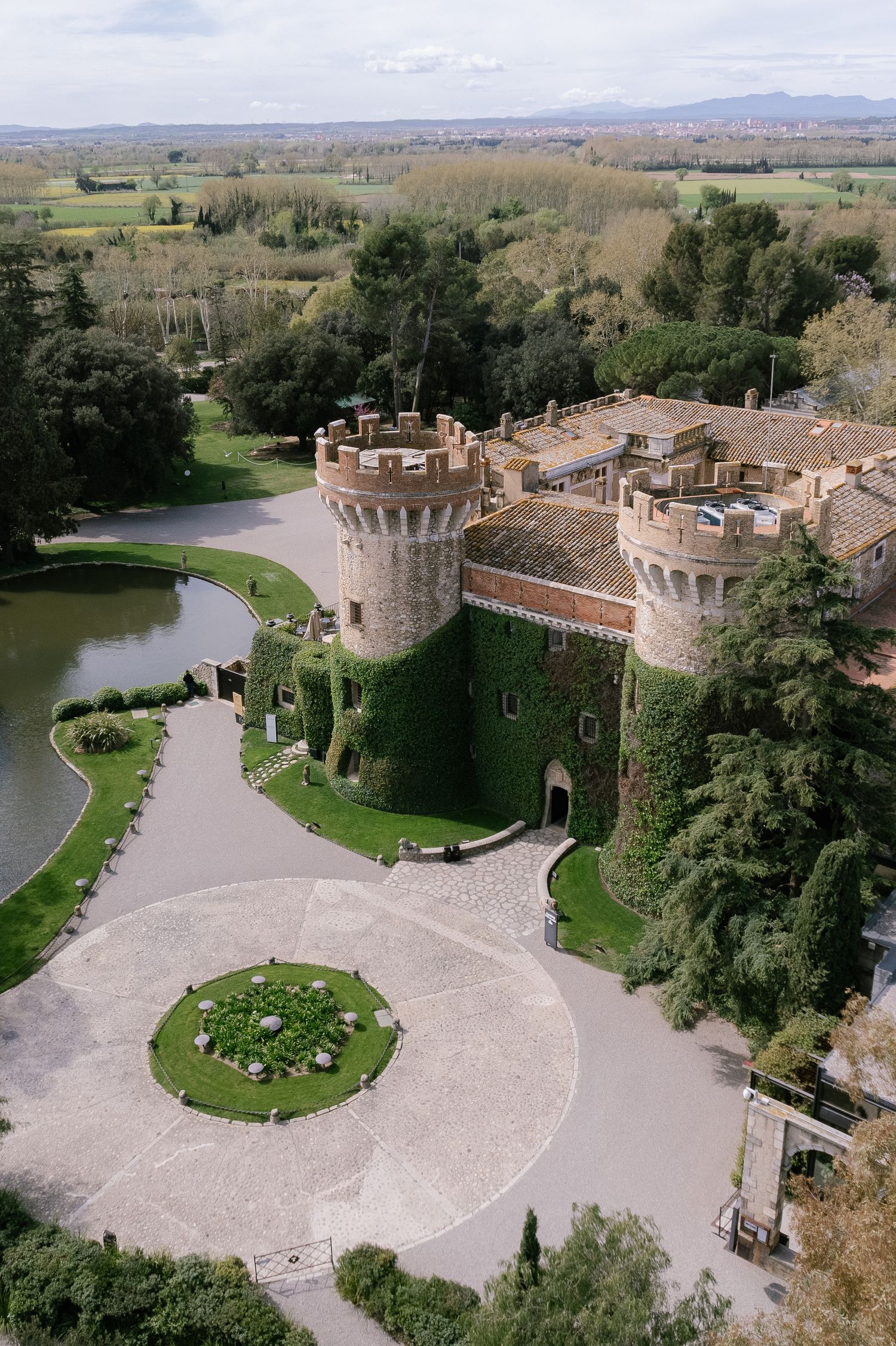 Aerial view of a medieval castle complex with curved driveway and manicured grounds.