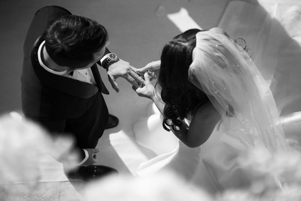 A black and white wedding photo showing a couple in formal attire during their ceremony.