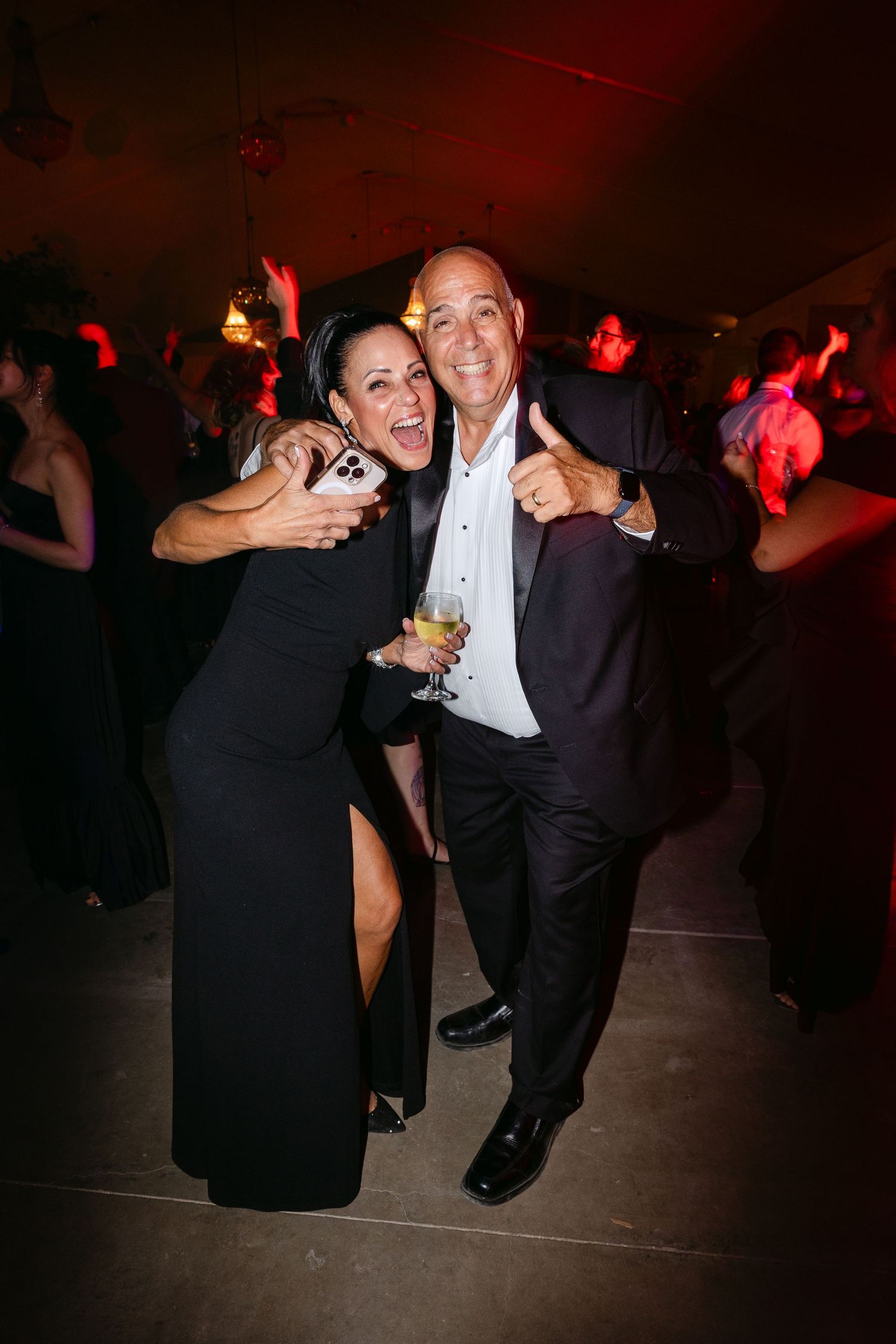 People dancing together at a formal event under red mood lighting.