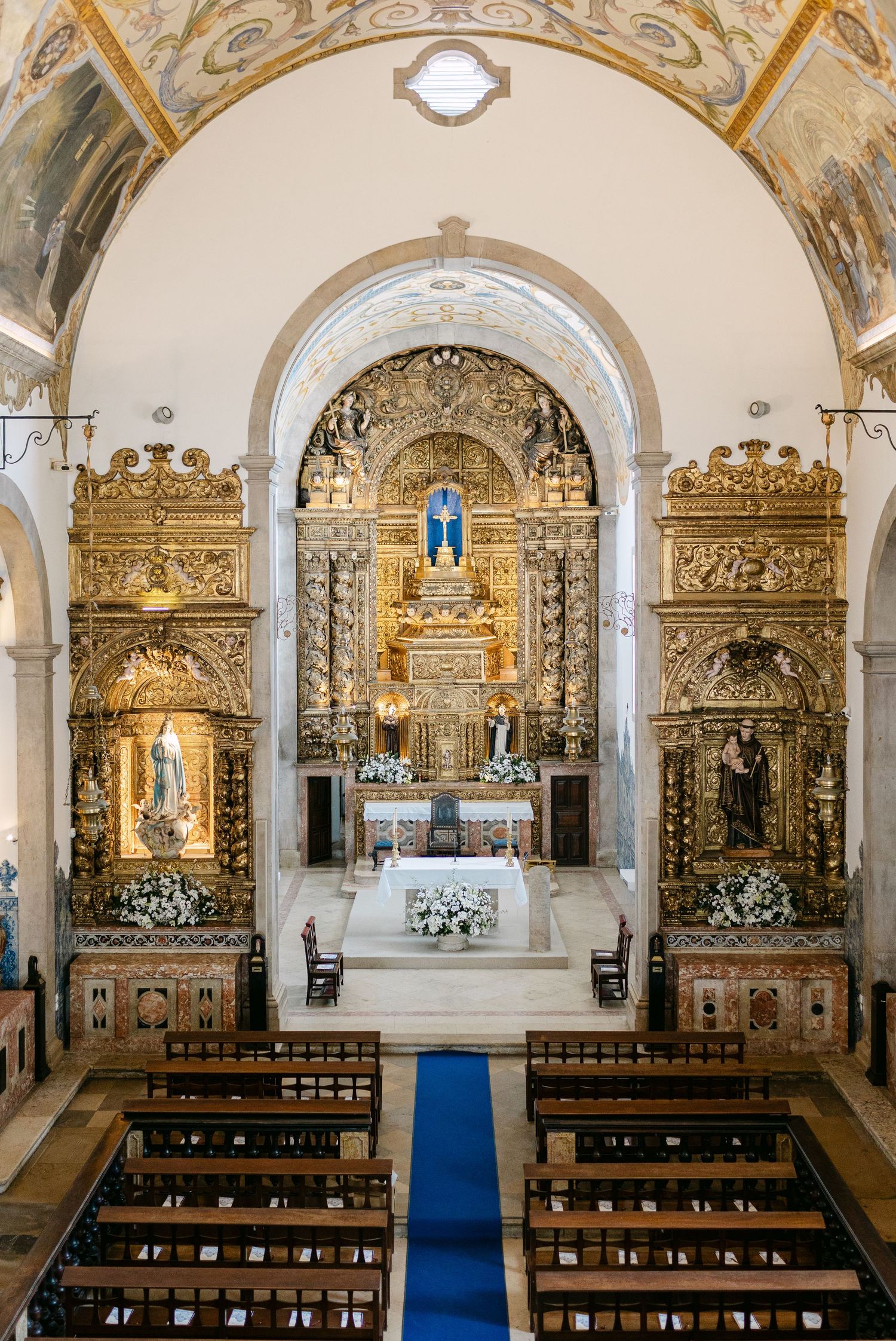 Interior of an opulent church with golden altars and ornate baroque architecture.