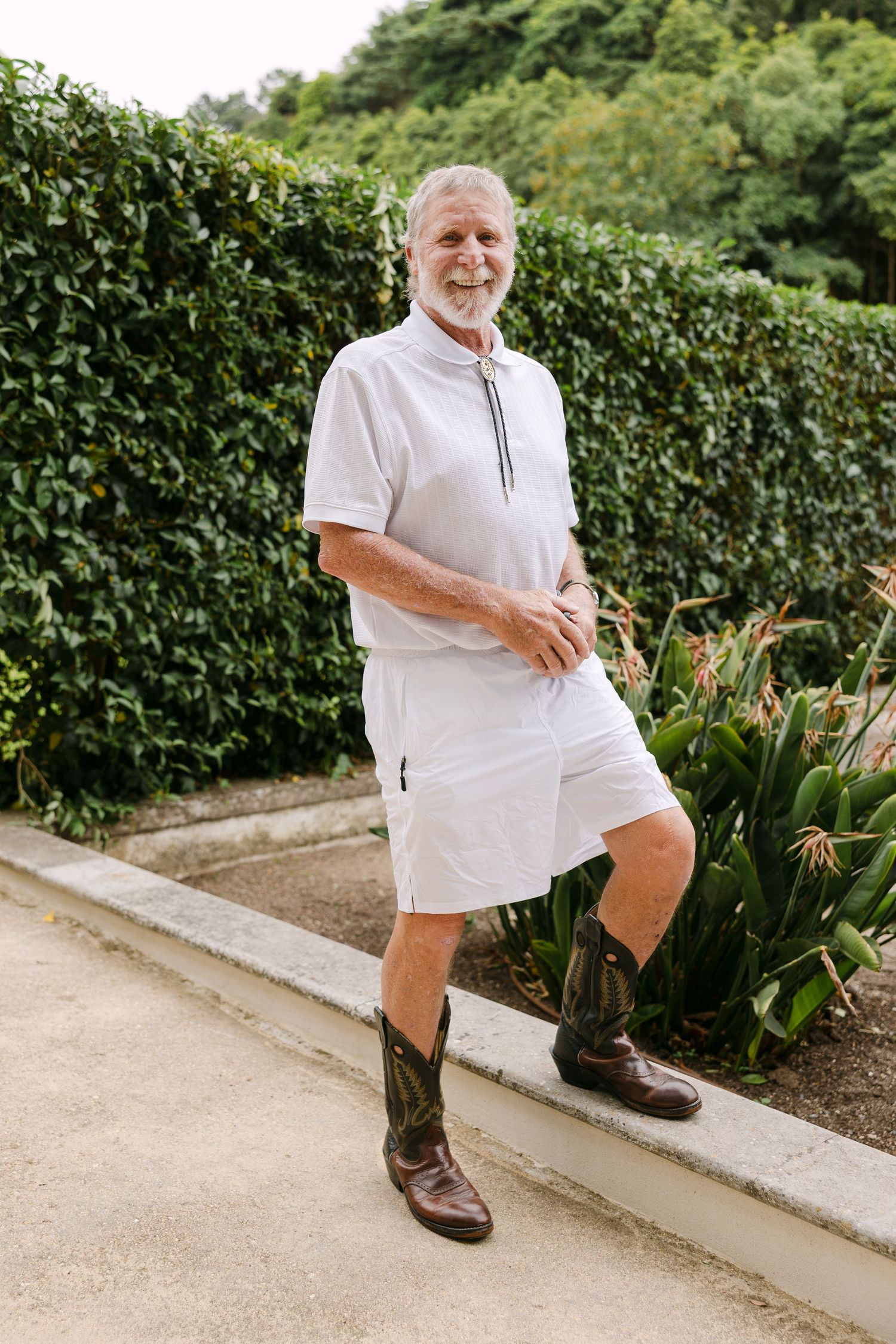 Sequence of playful poses on a garden path next to manicured hedges.
