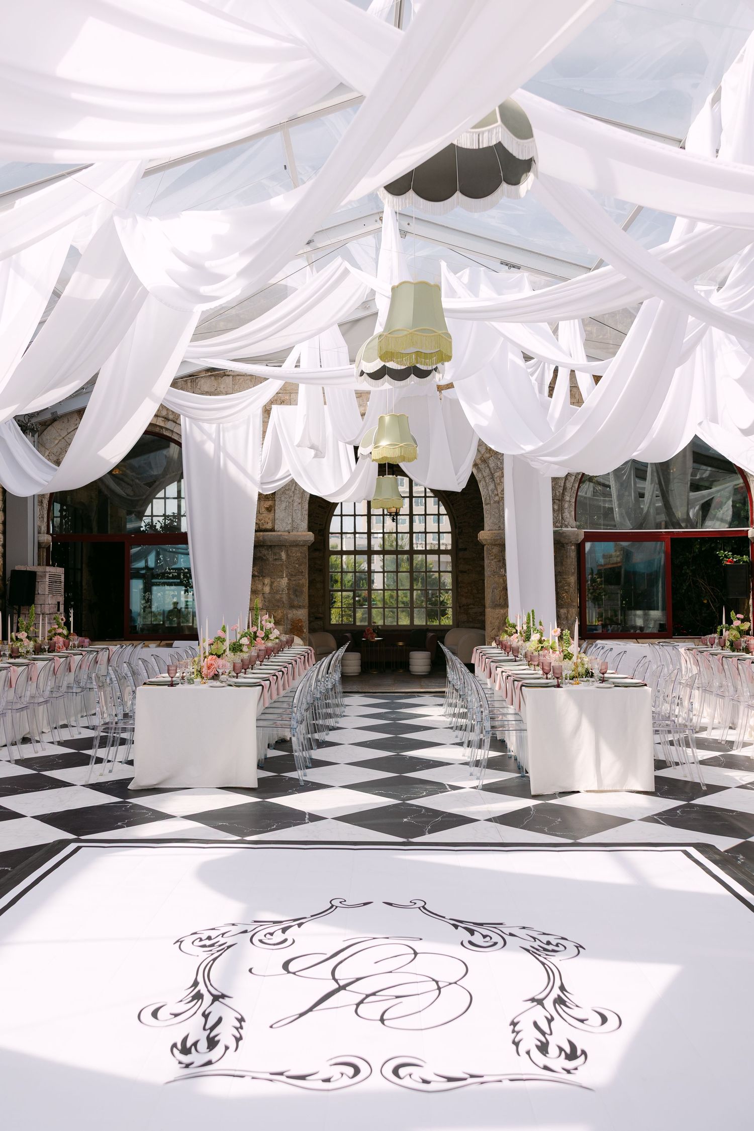 Wedding venue interior with flowing white fabric ceiling drapes and monogrammed dance floor.