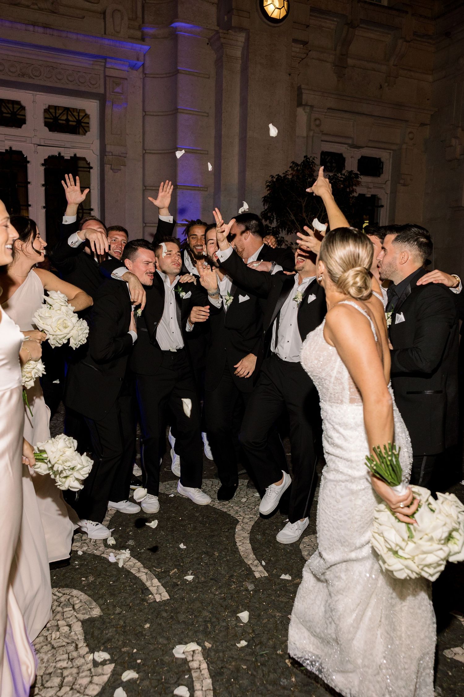 Wedding celebration with bridal party dancing in formal attire at an elegant venue.