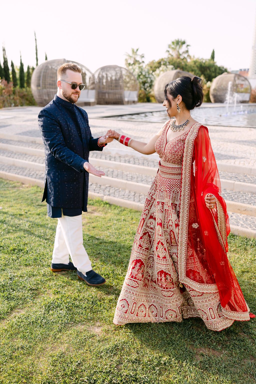 A romantic couple photoshoot on grass with traditional Indian bridal wear and western groom attire.