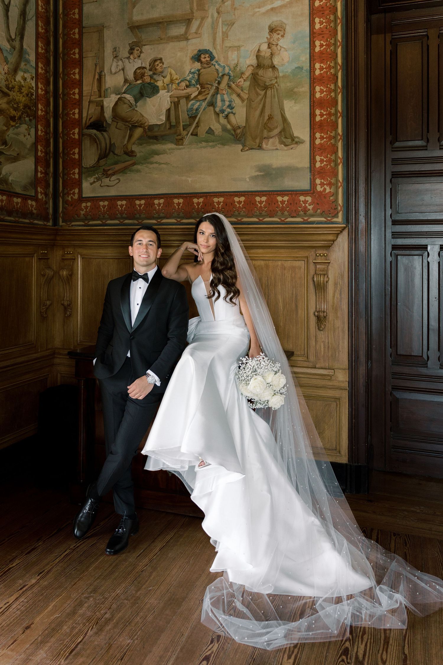 Formal wedding portraits in historic room with decorative wall paintings.