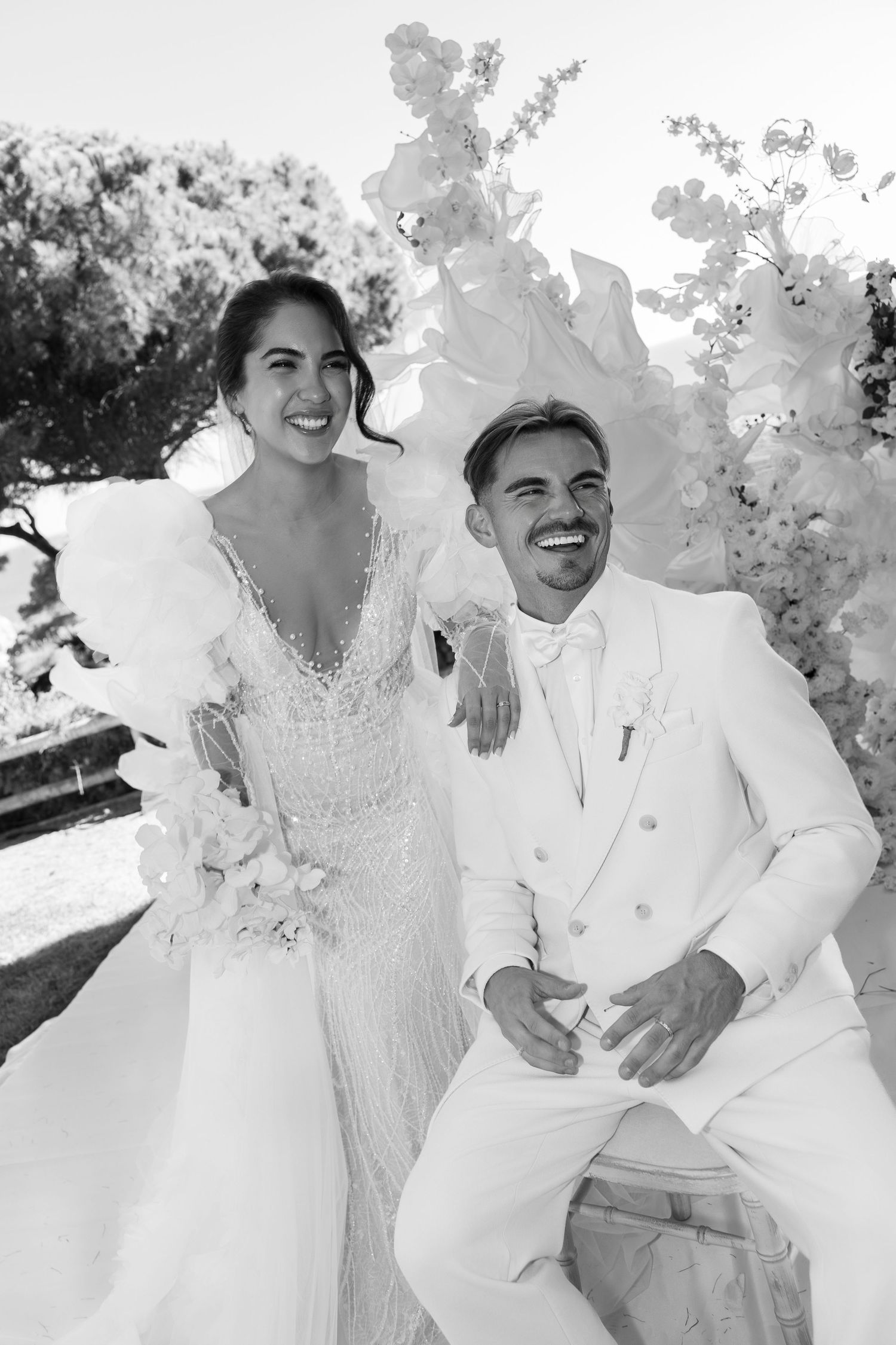 Artistic black and white portrait of wedding couple in all-white attire.