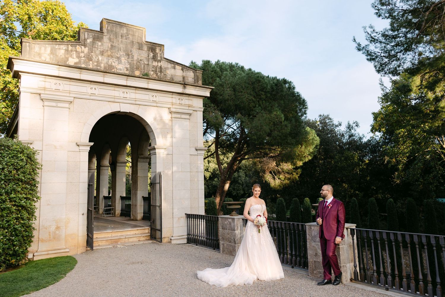 Elegant wedding portraits taken outside a stone building with arched doorways.
