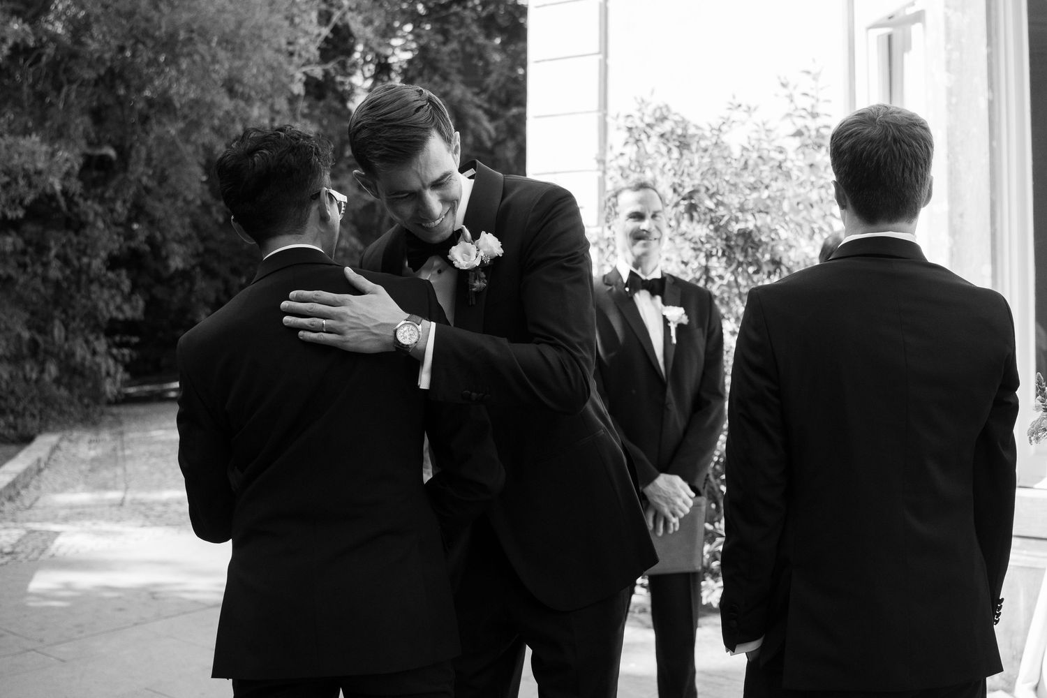 Black and white candid photos of groomsmen sharing moments before the ceremony.