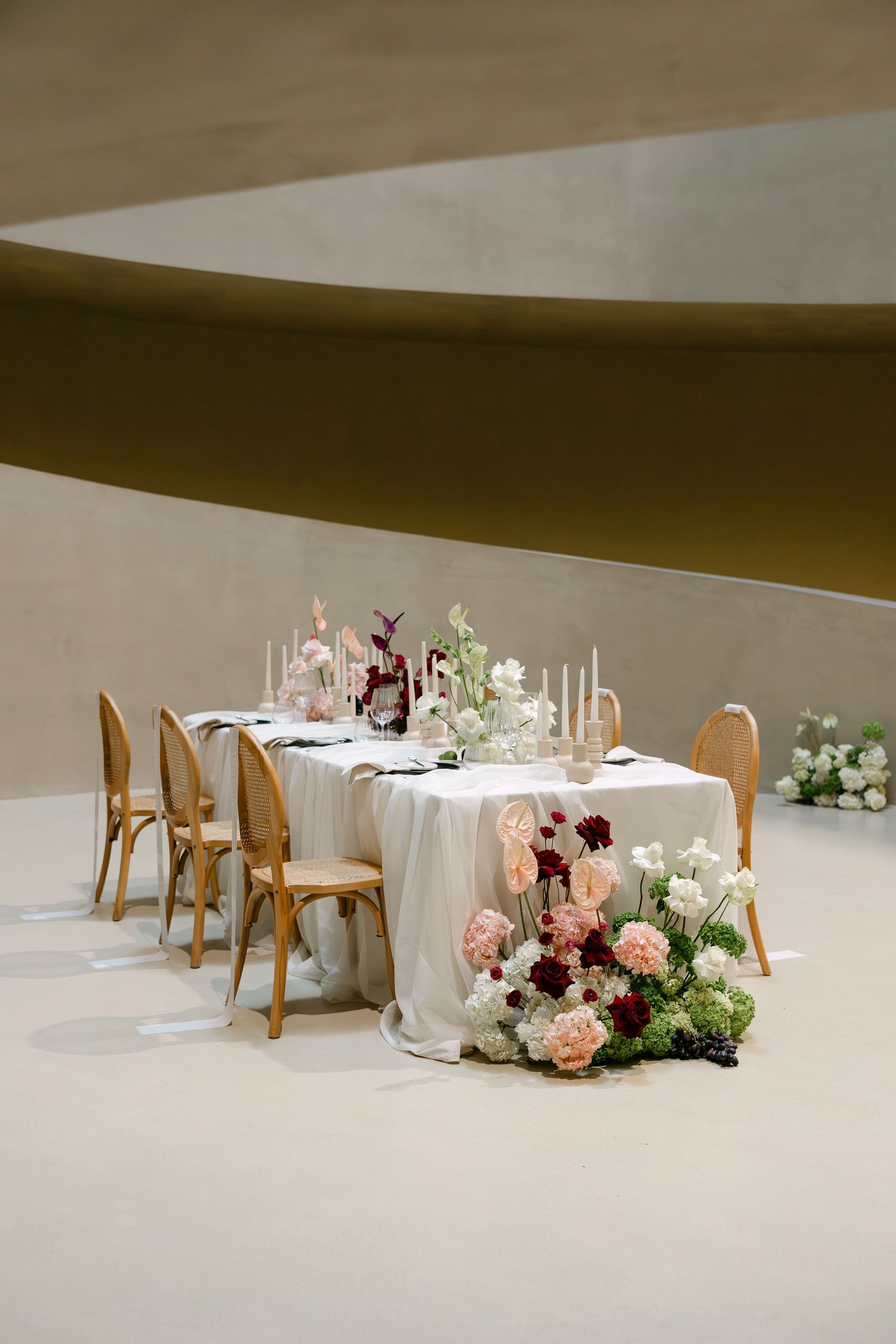 Wedding reception tables decorated with pink and white floral arrangements in a contemporary venue.