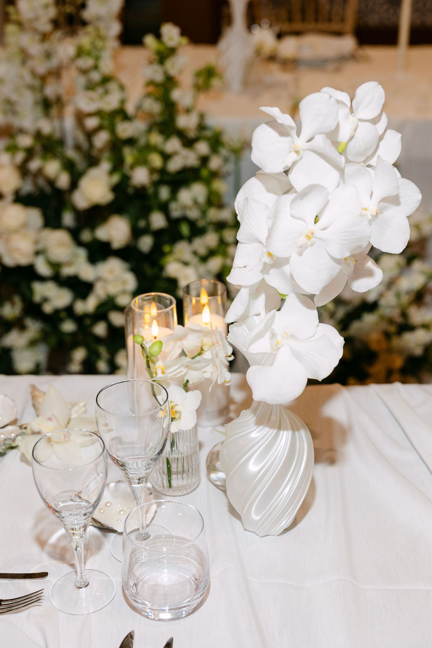 Elegant table setting with white orchids, crystal glasses and candlelight.