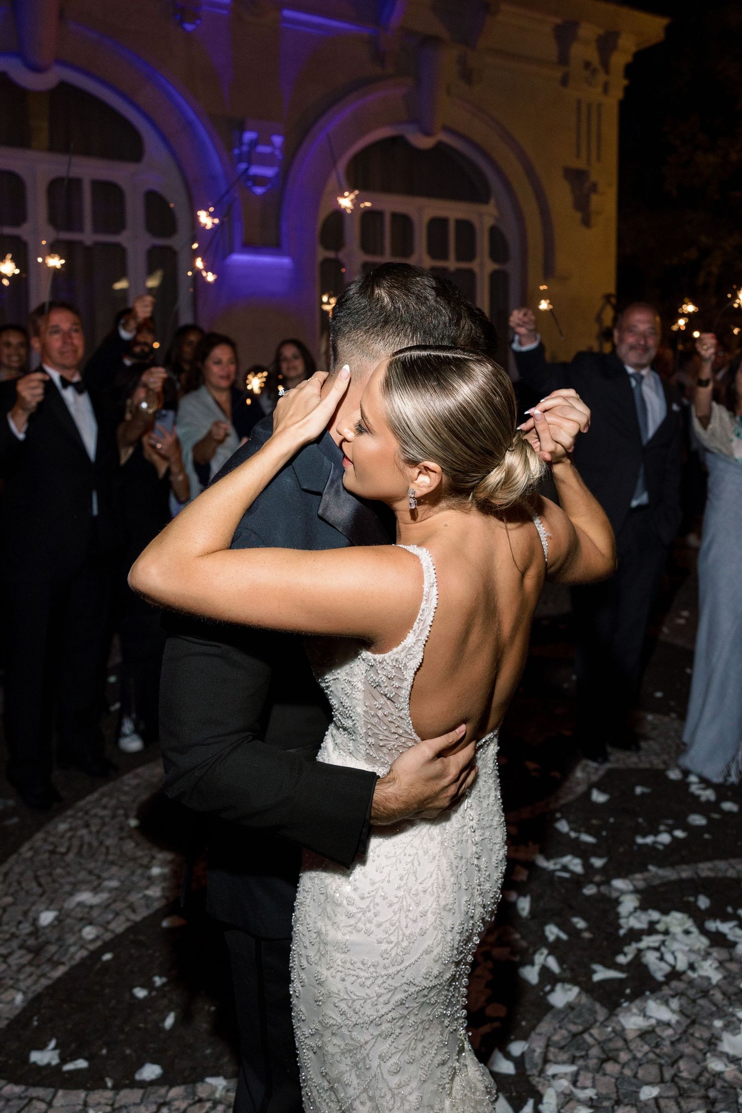 Wedding celebration with dancing and confetti at an ornately decorated venue with blue lighting.