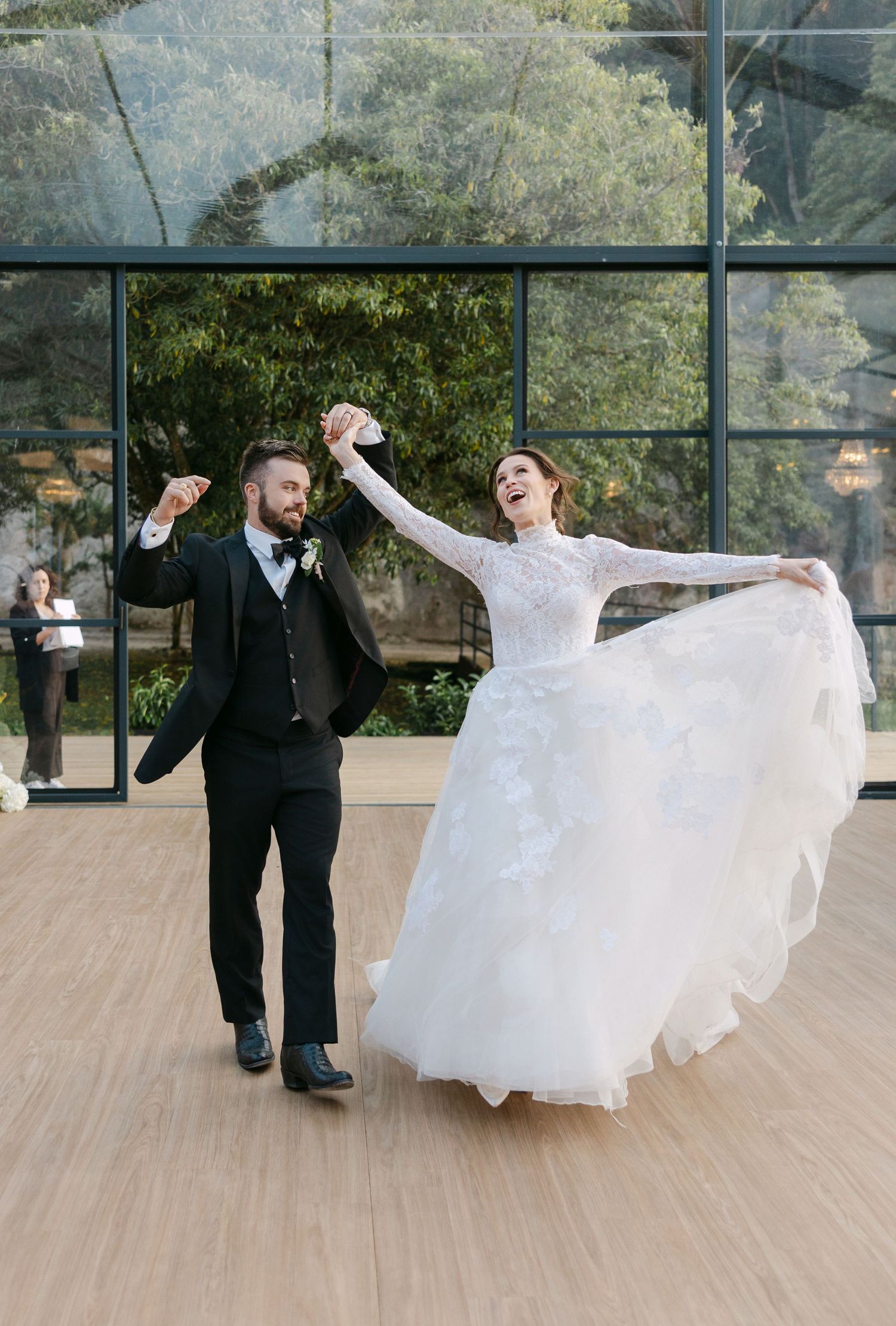 Sequence of newlyweds dancing and twirling in a bright glass-walled venue.