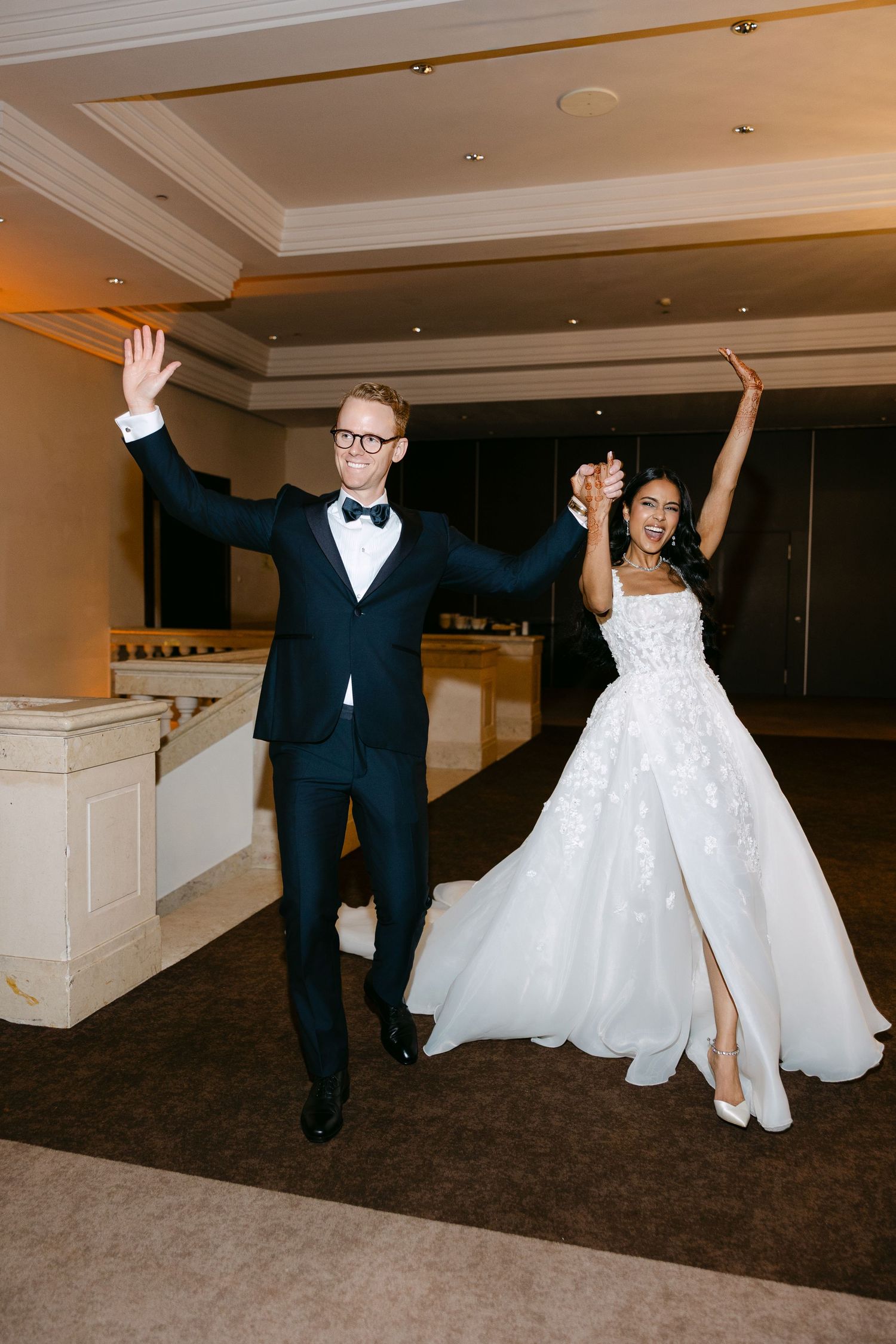 Joyful newlyweds dance with raised arms during their wedding celebration.