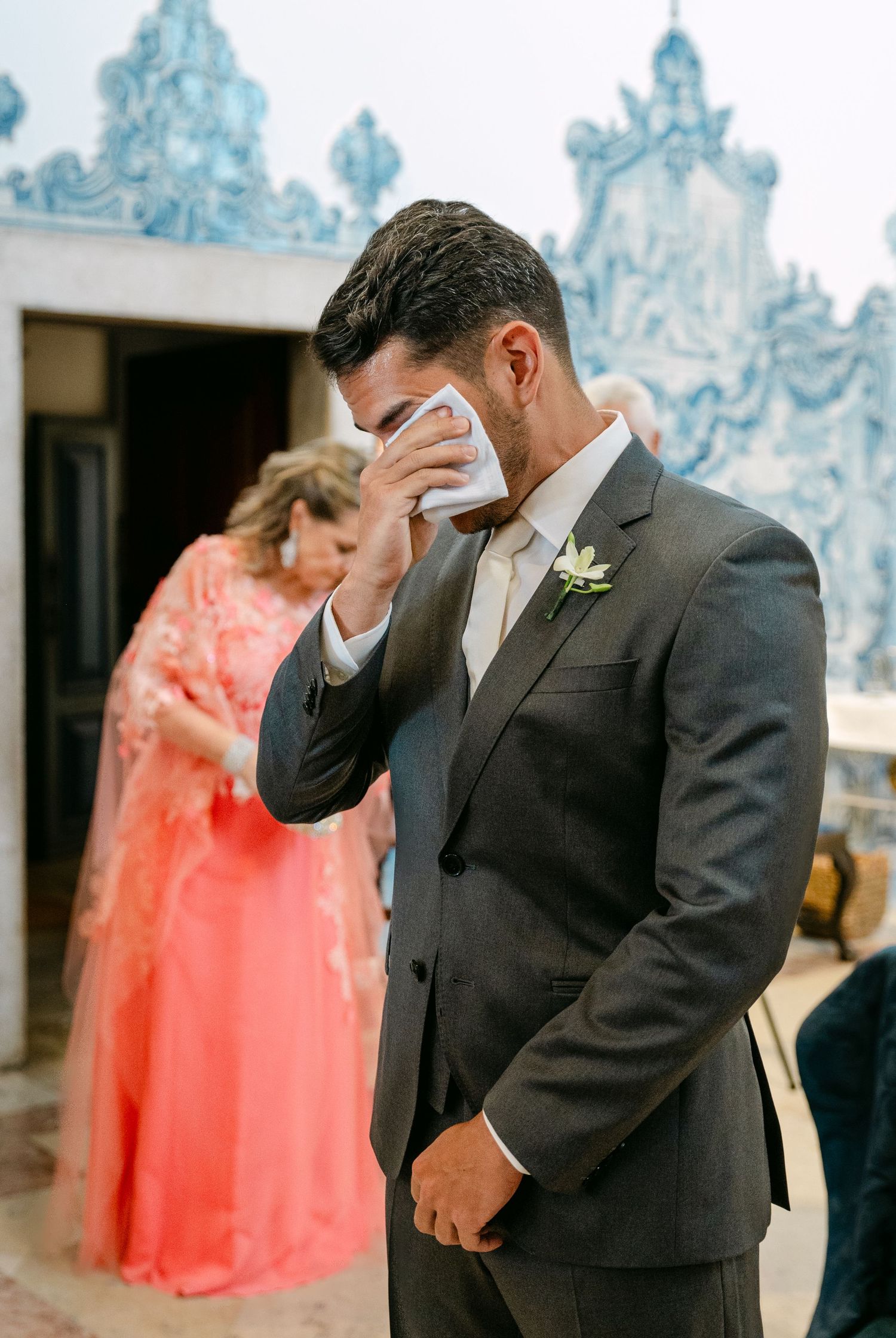 An emotional moment captured during a wedding against blue and white tiled walls.